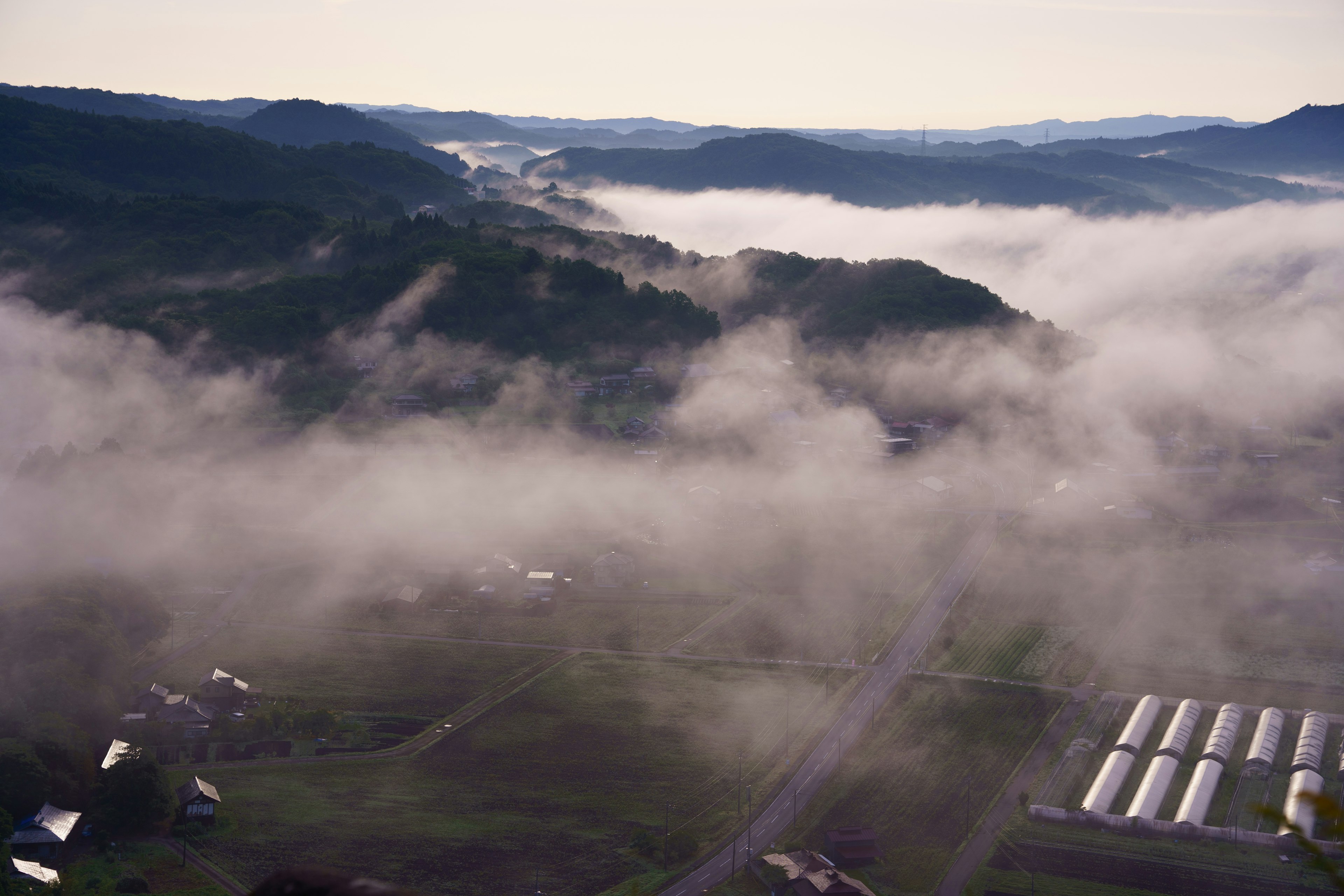 Un paesaggio di colline e campi avvolti nella nebbia