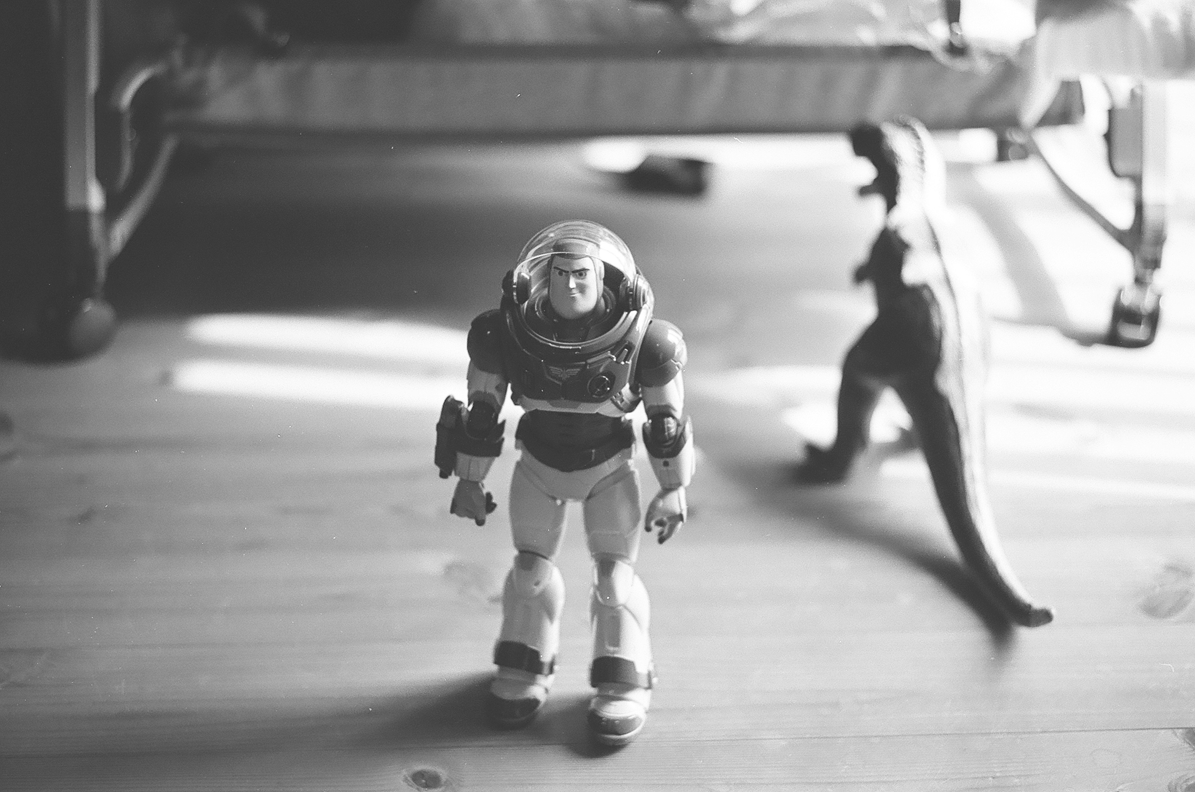 Toy astronaut in a spacesuit standing near a dinosaur in a room