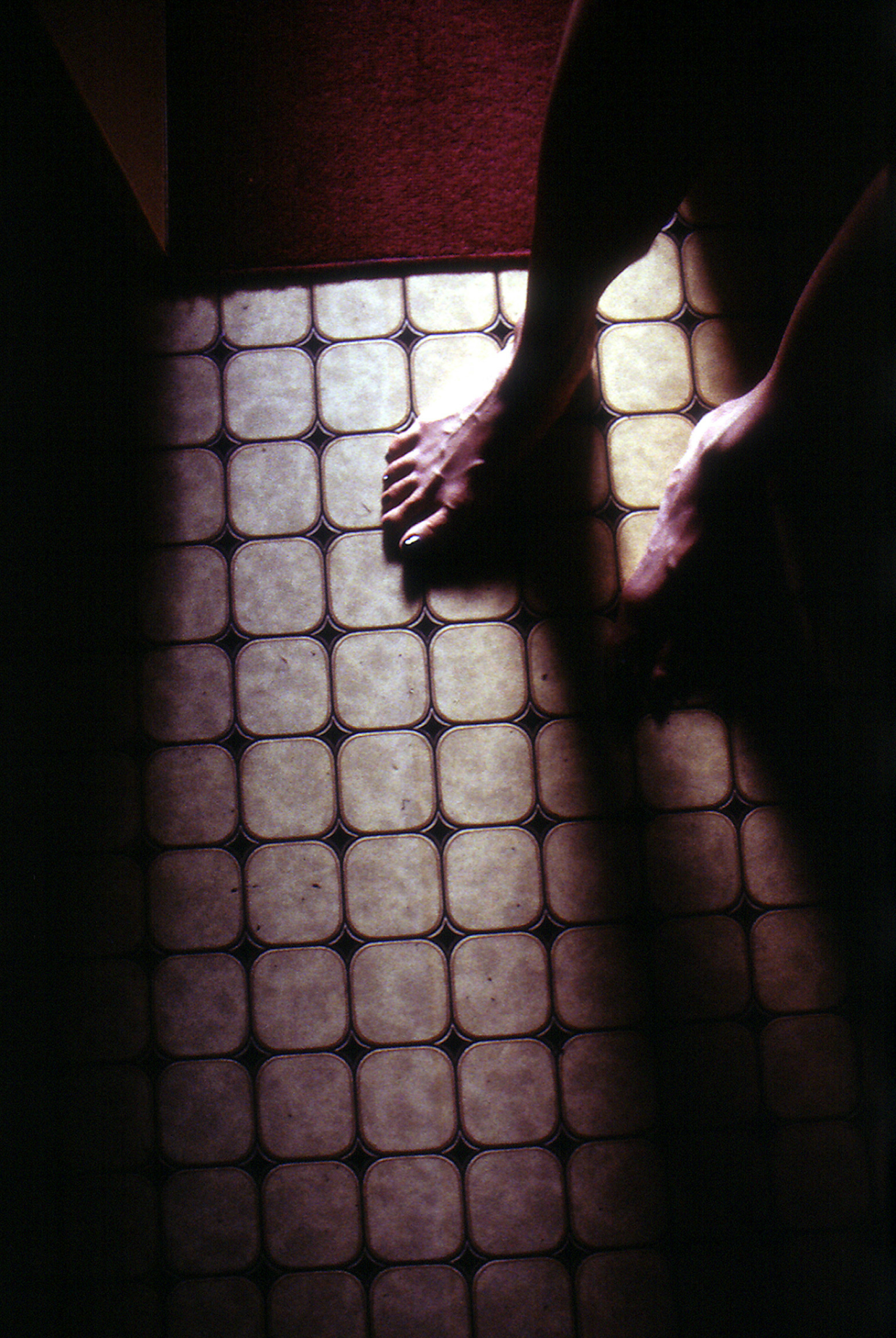 Bare feet standing on tiled floor with shadow play