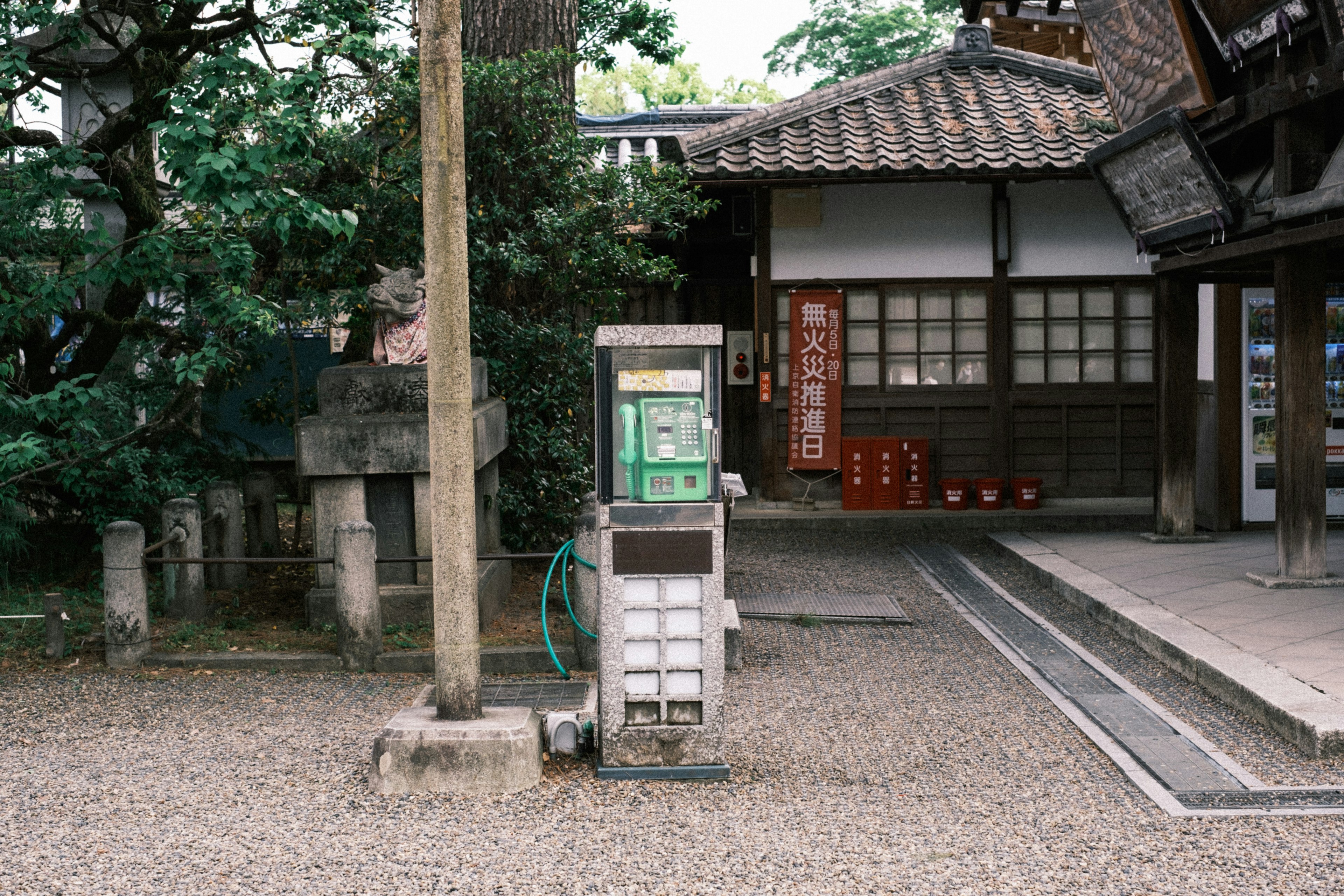 An old telephone booth next to a traditional Japanese house in a tranquil setting