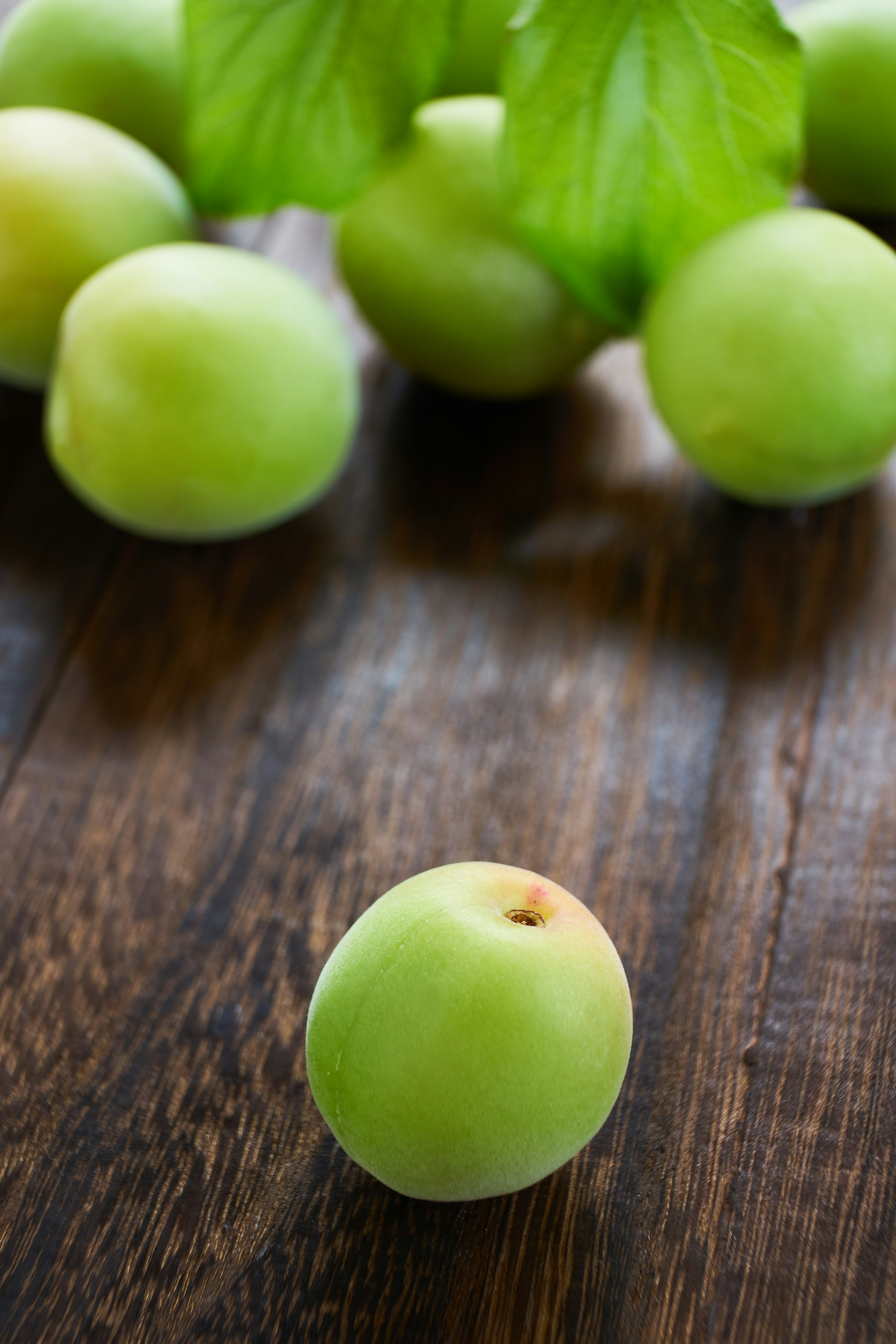 Eine Gruppe grüner Äpfel auf einem Holztisch mit Blättern