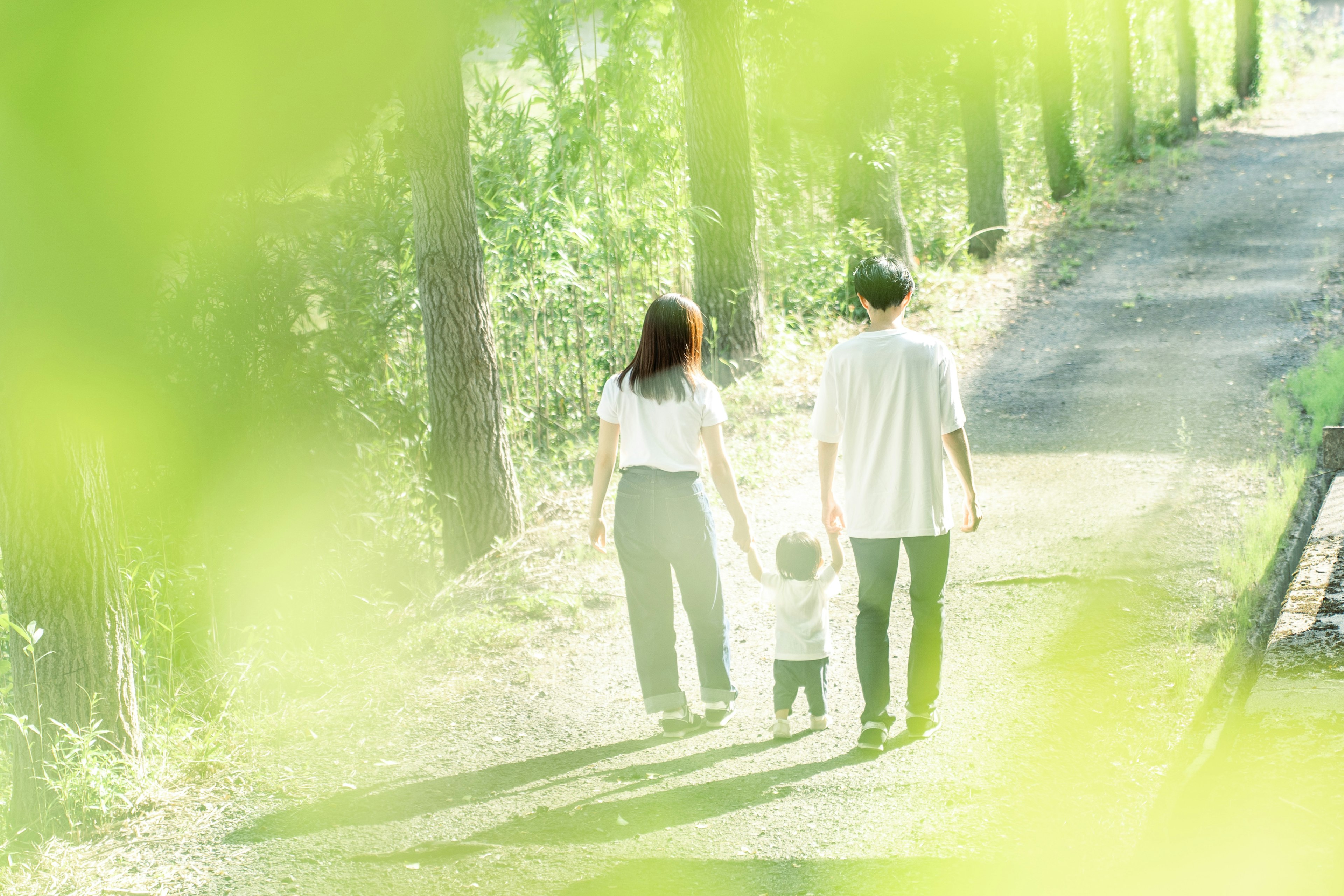 Family walking on a path surrounded by green leaves