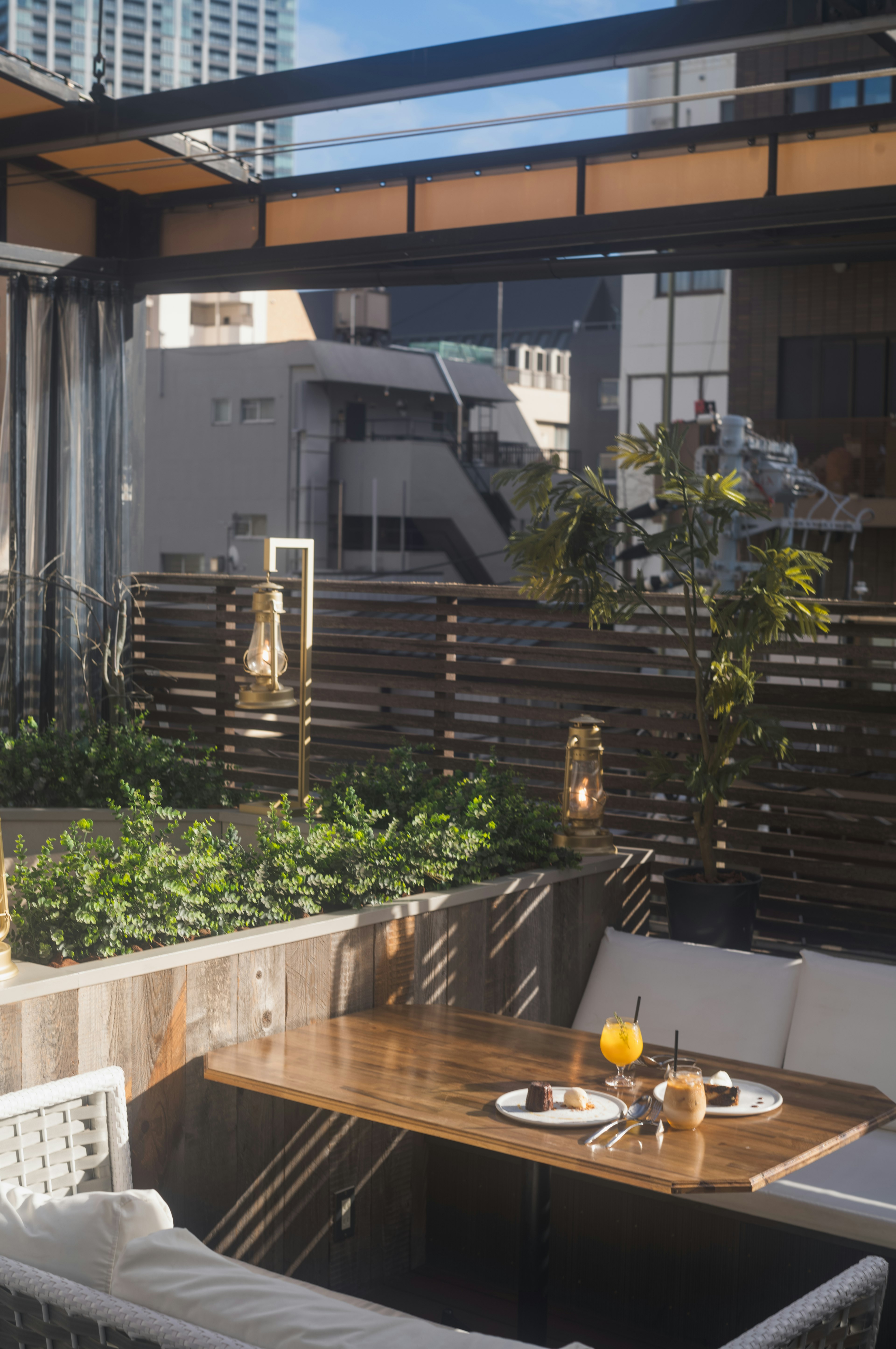 Terrasse extérieure avec une table en bois et un canapé entouré de verdure