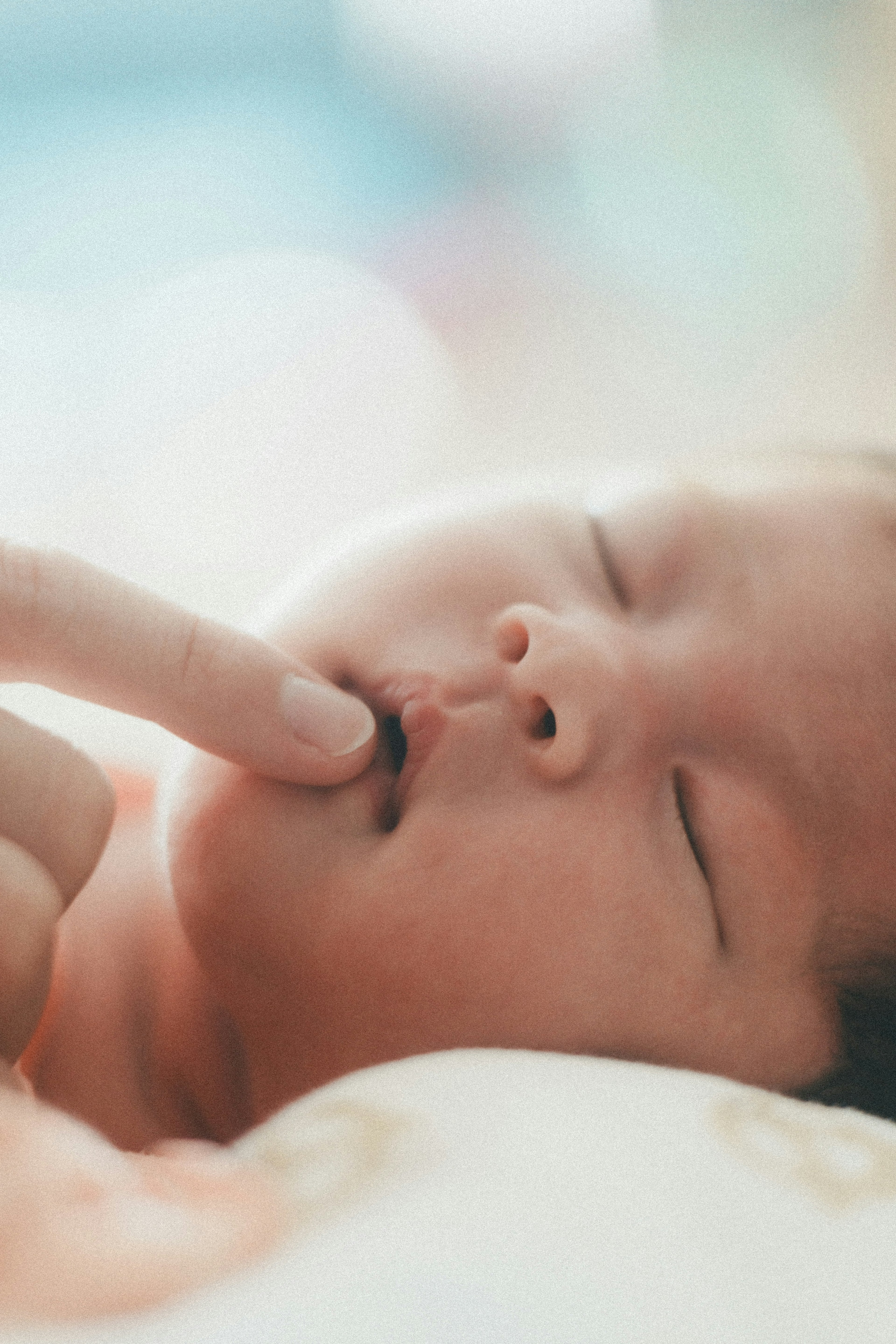 A sleeping baby with a finger gently touching its mouth