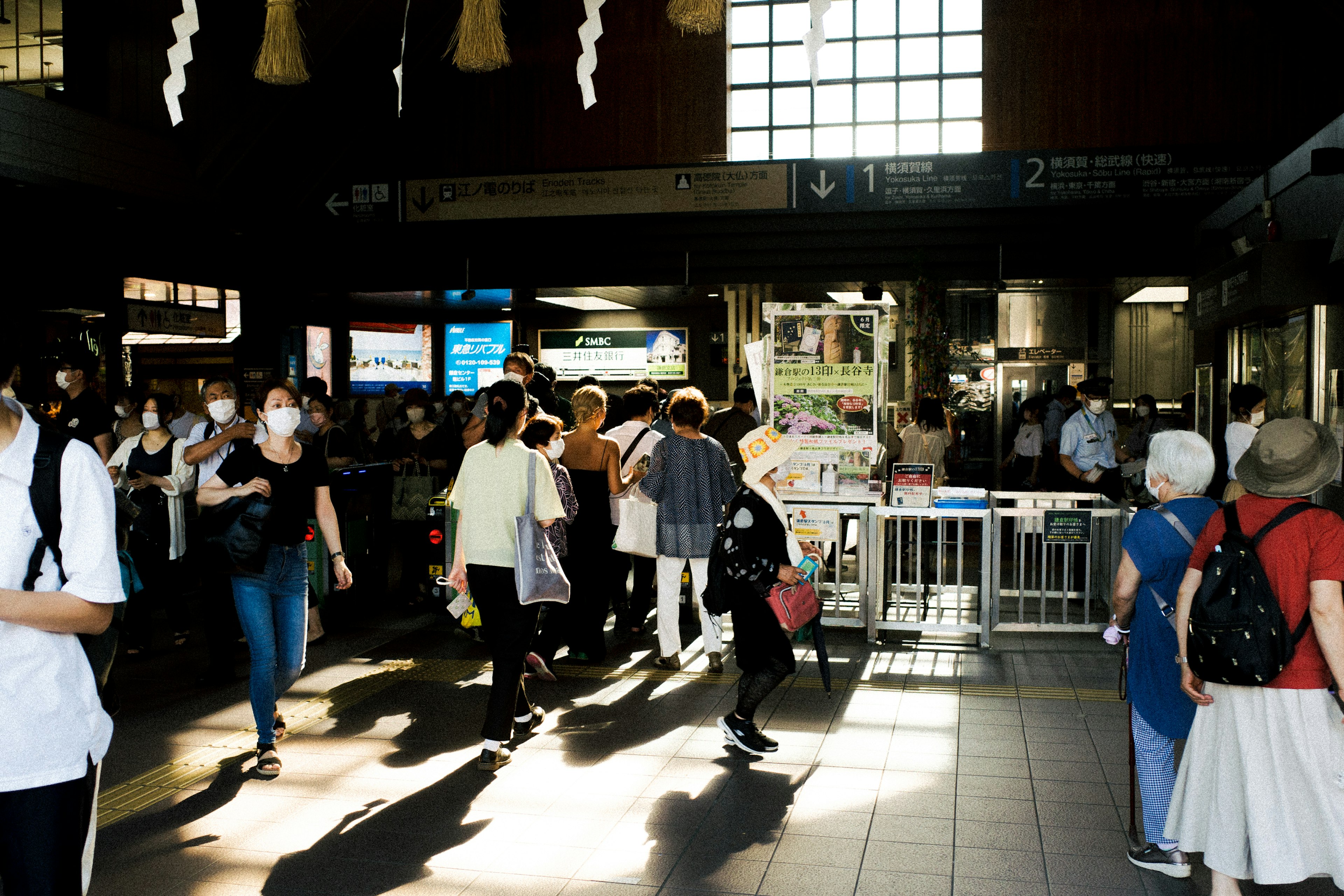 Belebte Innenseite eines Bahnhofs mit Menschen, die gehen Helles Licht und sich kreuzende Schatten