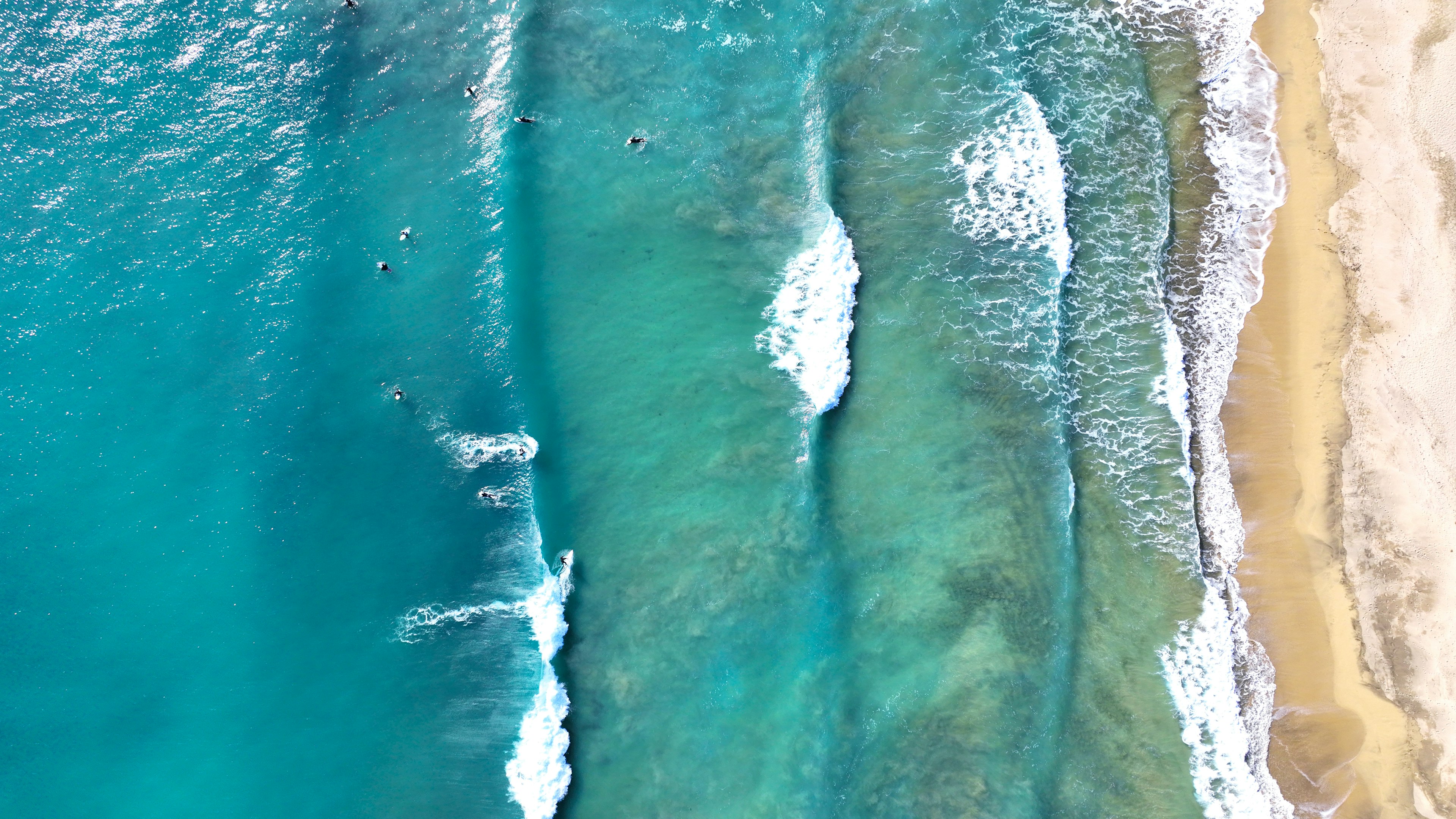 Vista aérea de olas turquesas y playa de arena