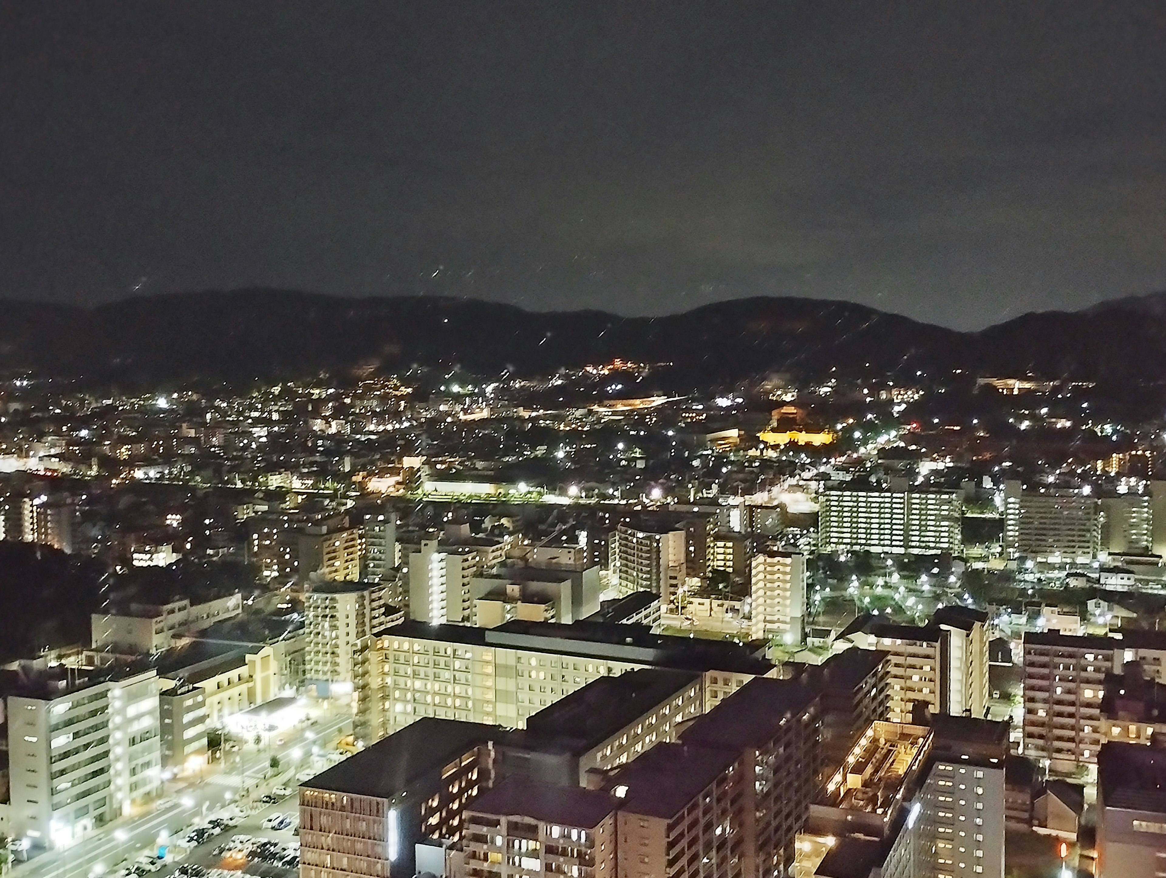 夜景の都市風景 高層ビルと山々の景観