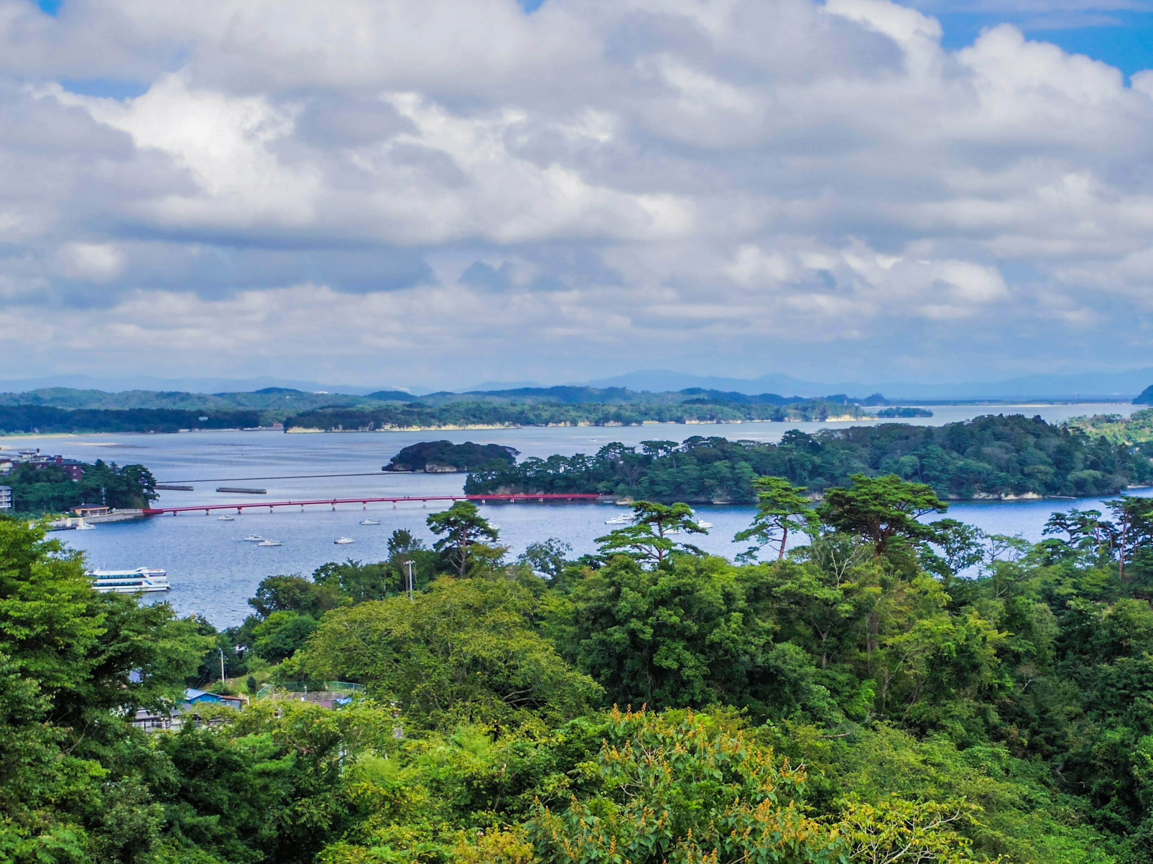 Scenic view of a lake surrounded by lush greenery and cloudy sky