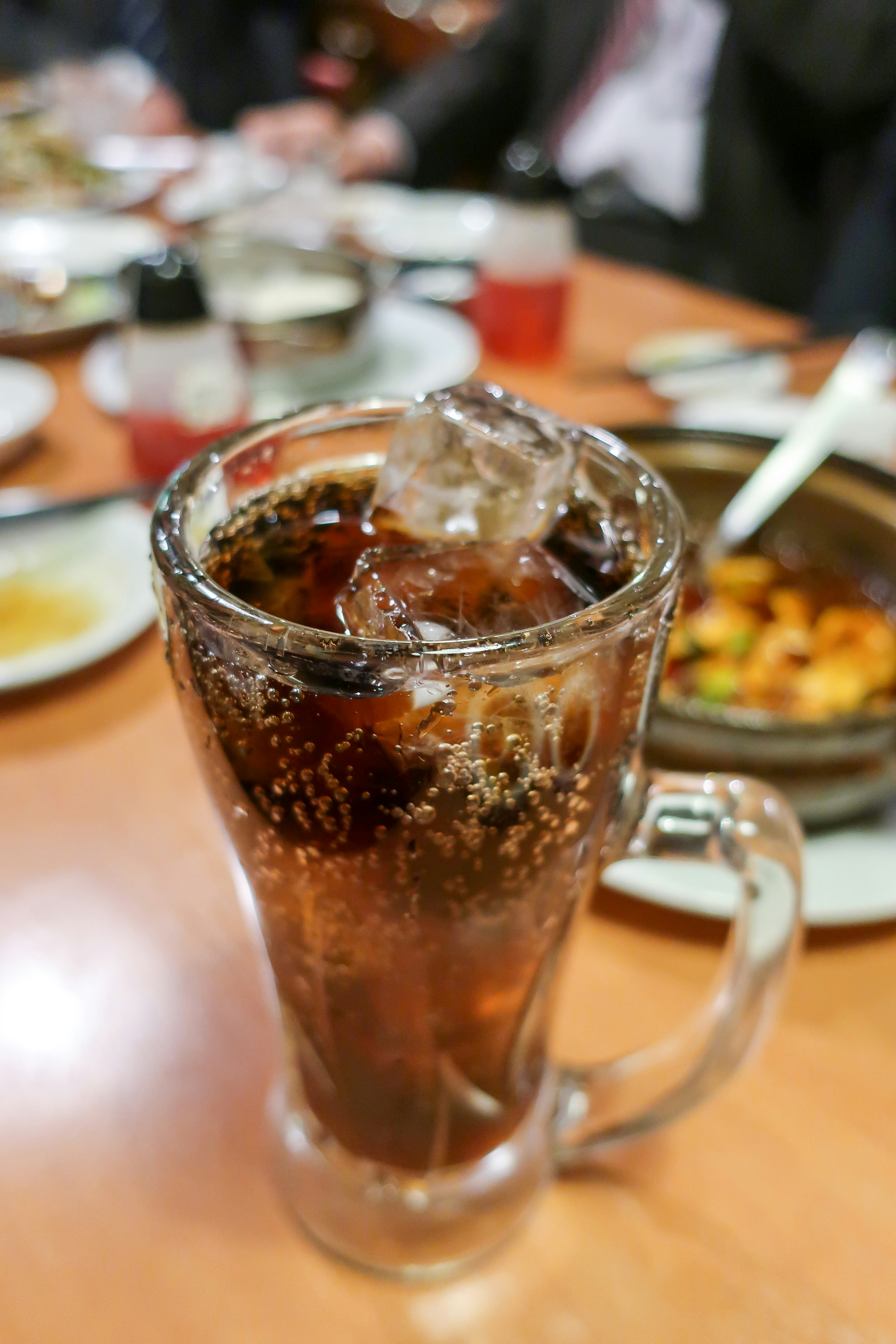 Ein Glas Cola mit Eiswürfeln auf einem Holztisch