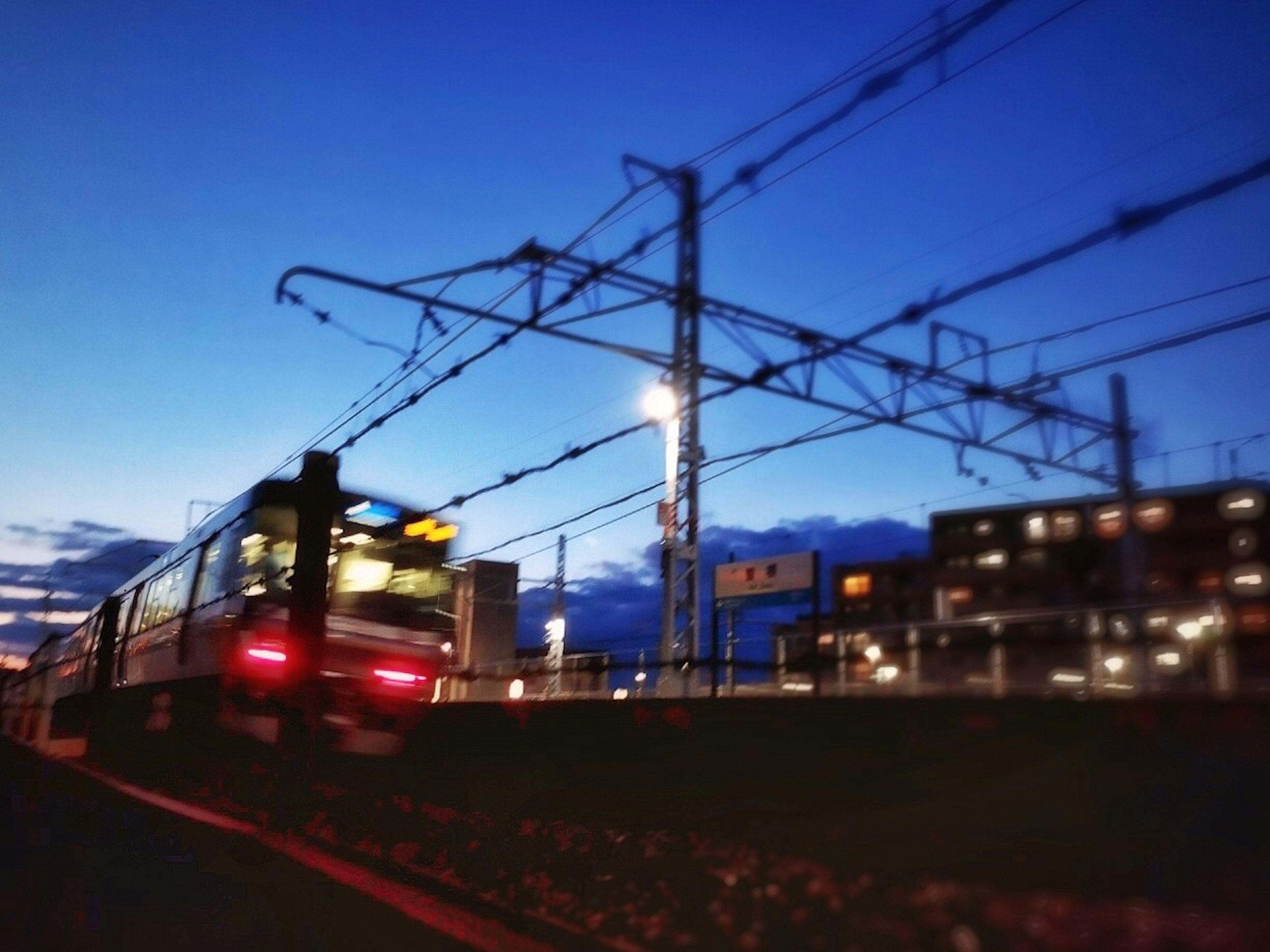 Train se déplaçant au crépuscule avec des lignes aériennes et des bâtiments urbains