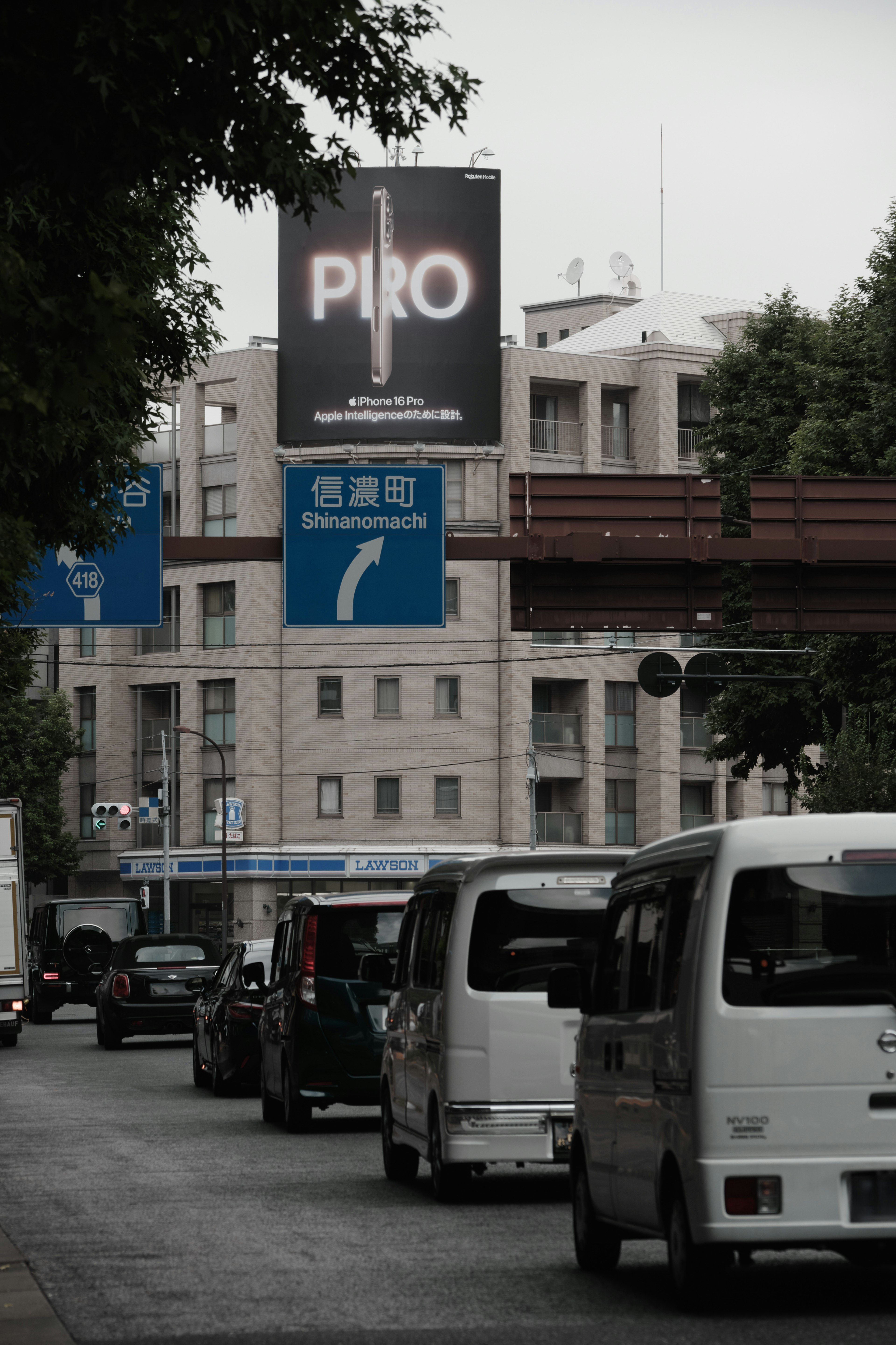 City street scene featuring a billboard and a line of vehicles