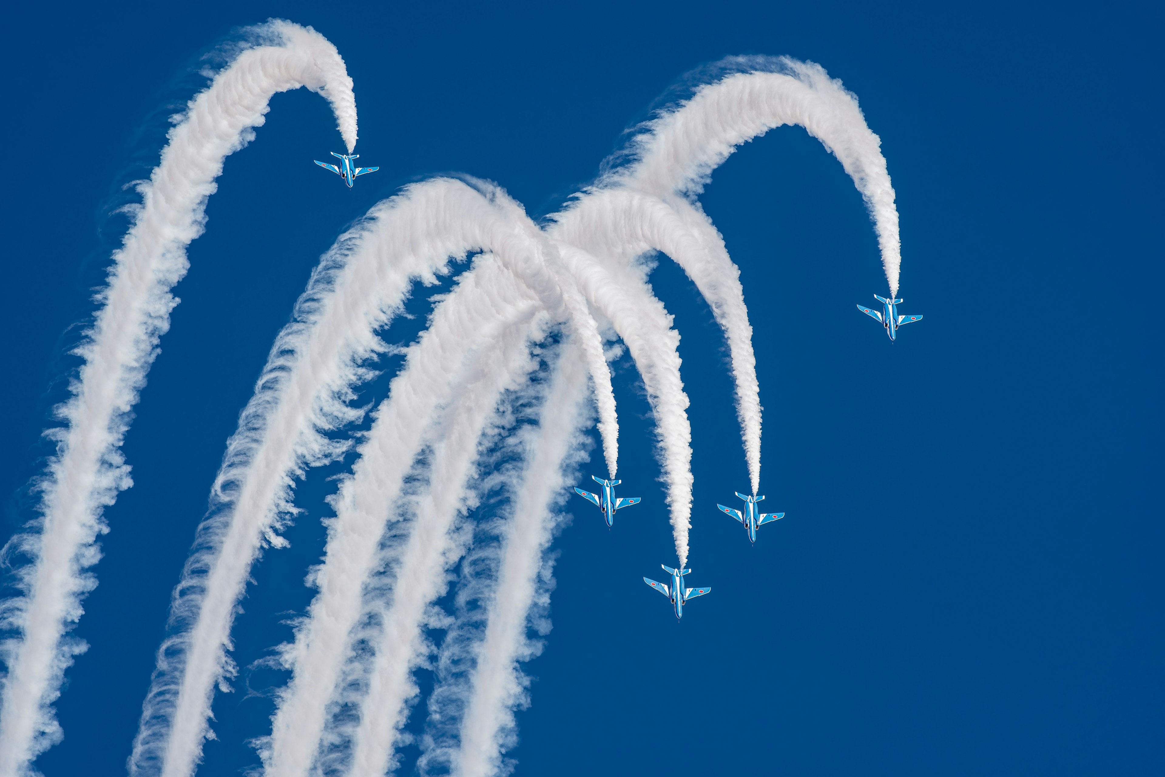 青空に舞う飛行機の白い煙の弧