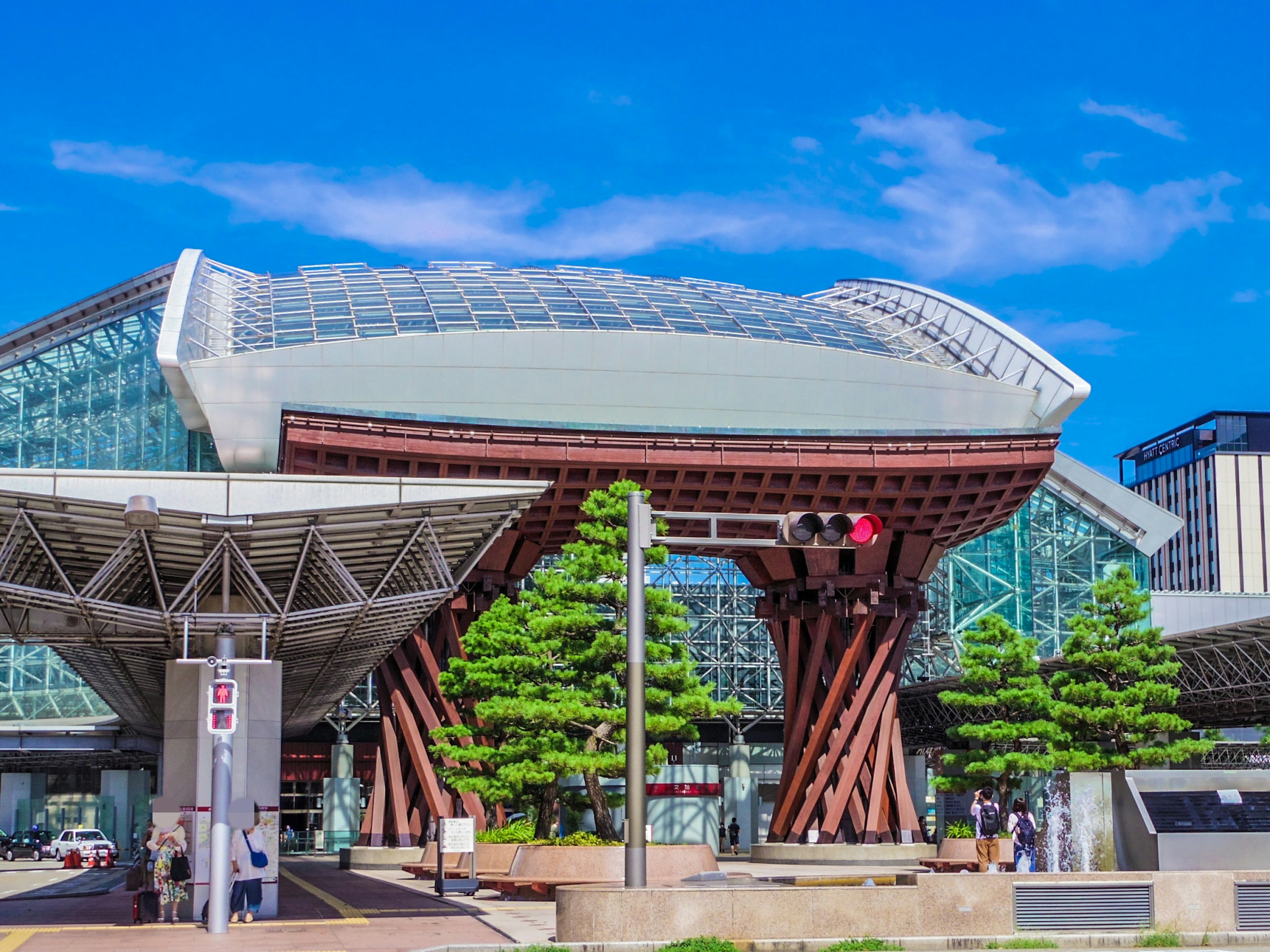 Gare moderne avec un design en verre et en bois sous un ciel bleu dégagé