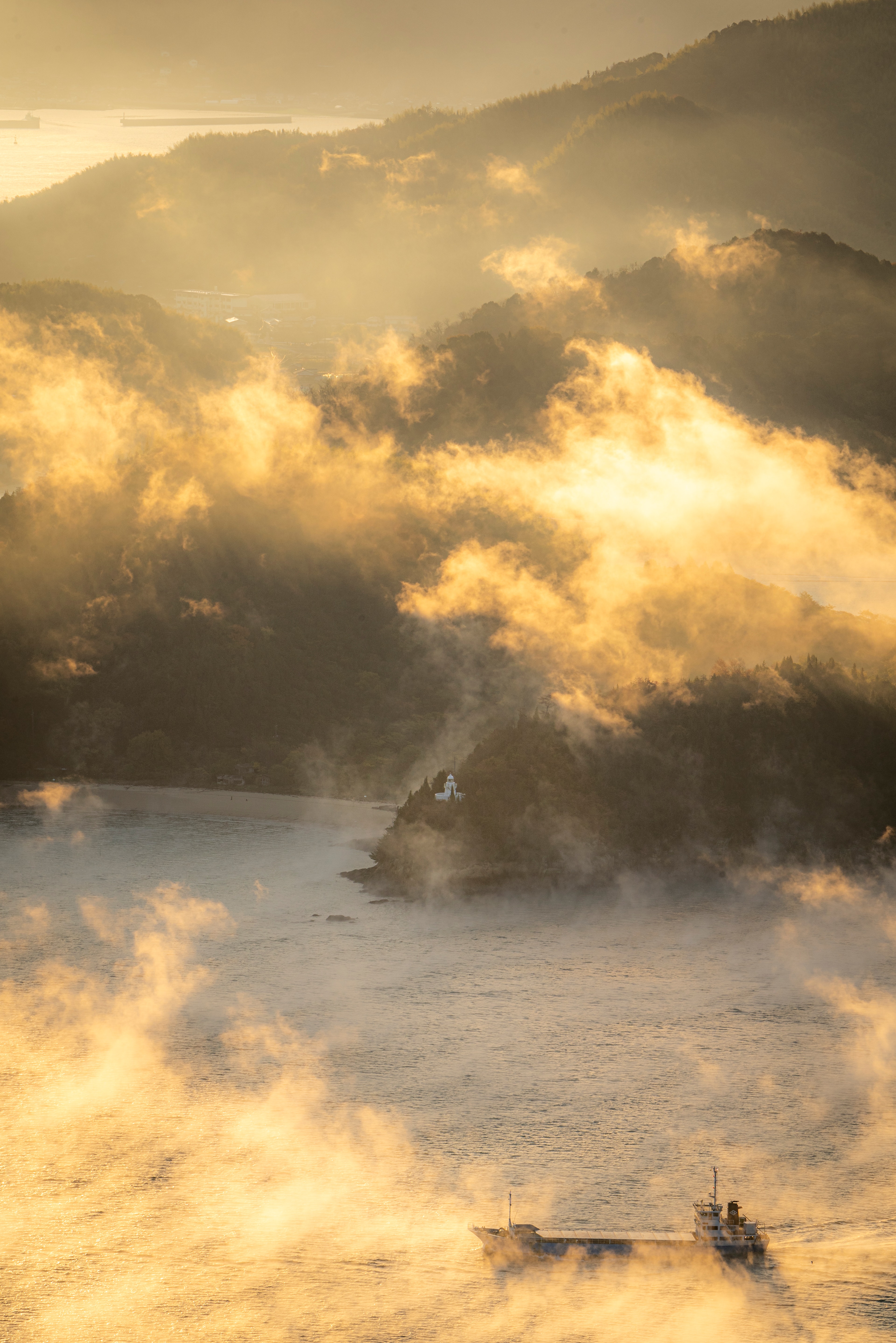 Scenic view of mountains and sea enveloped in golden mist