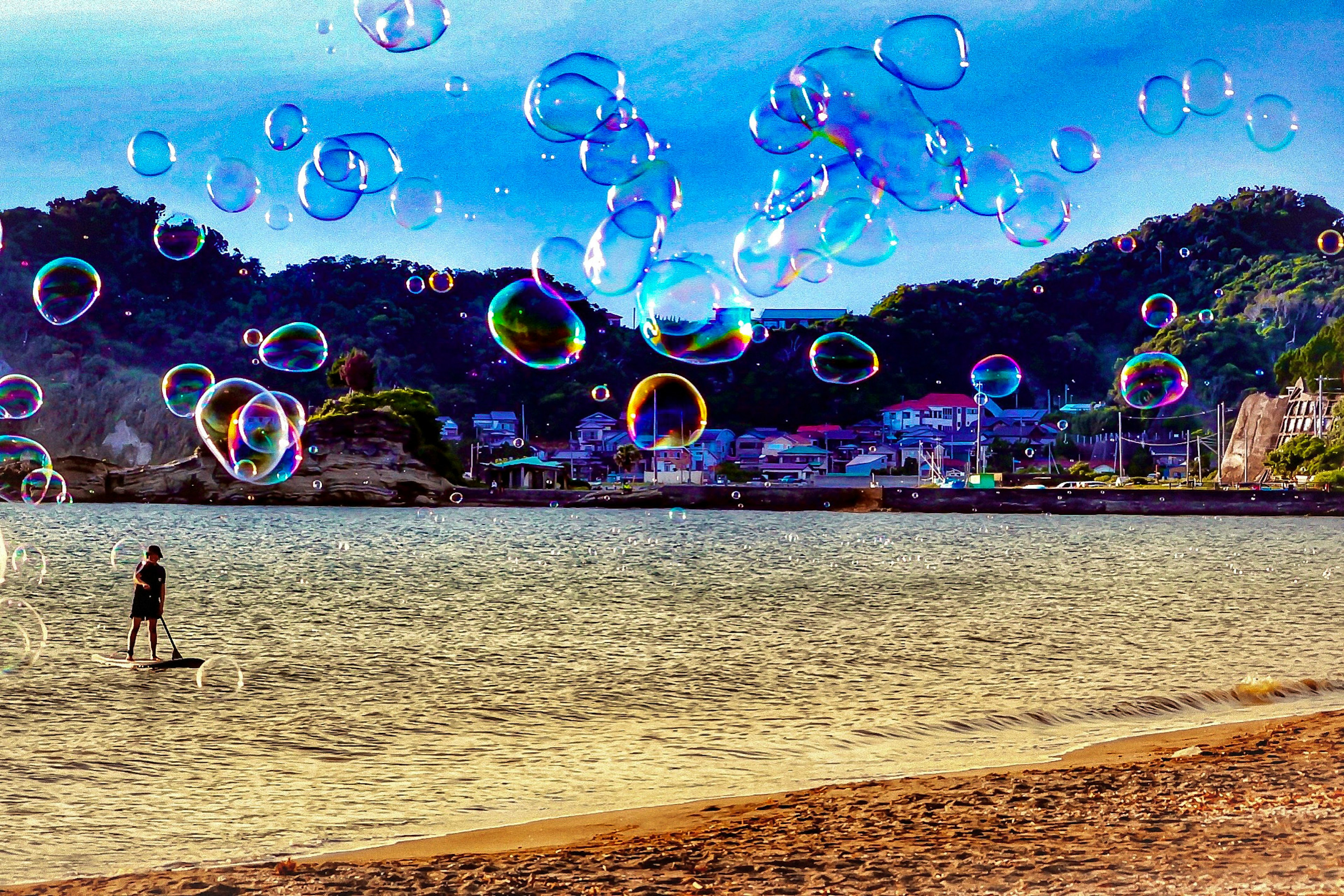 A beach scene with colorful bubbles floating and a person in the water