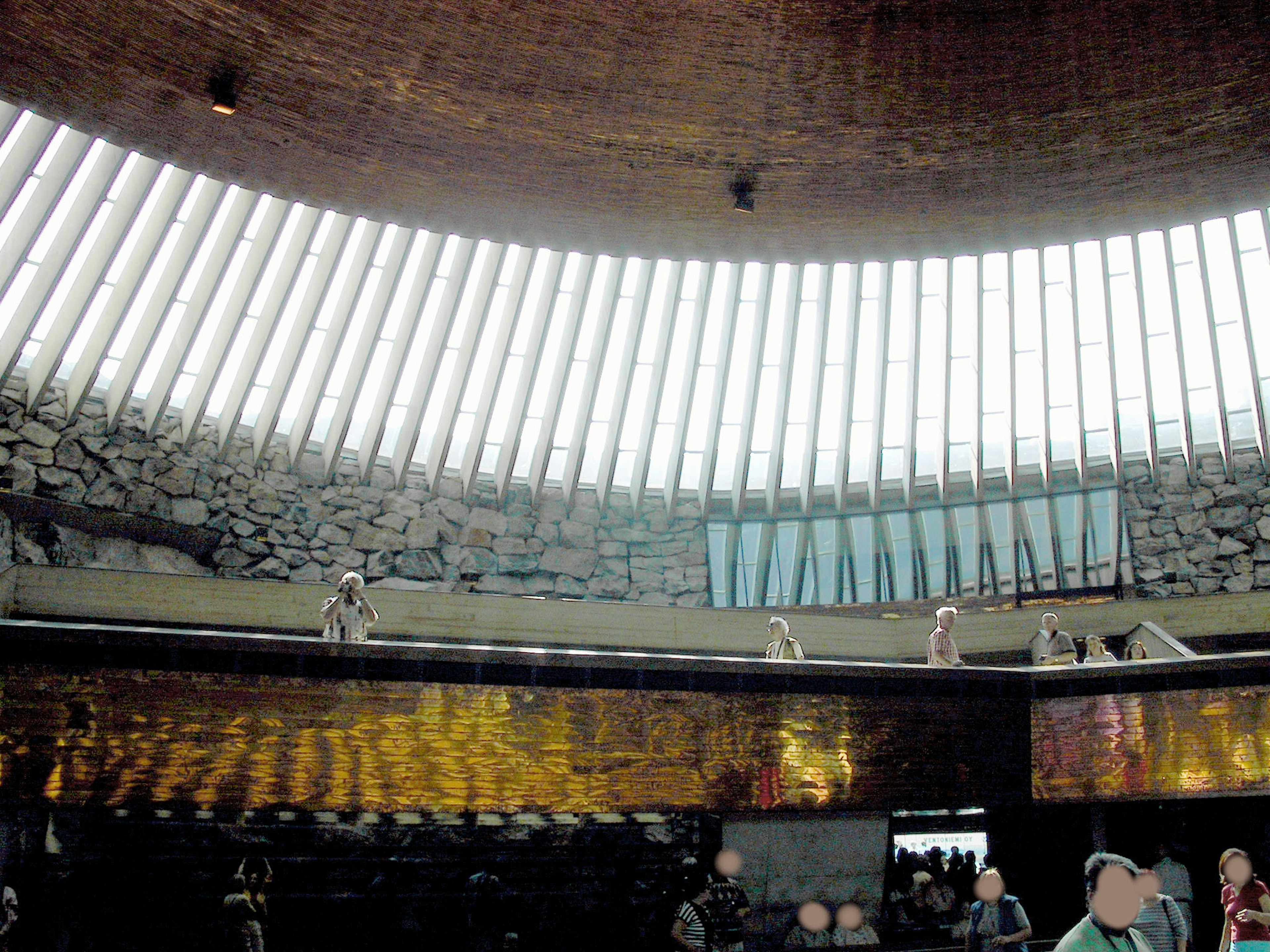 Intérieur d'un bâtiment circulaire avec de grandes fenêtres laissant entrer la lumière naturelle et des murs en pierre visibles