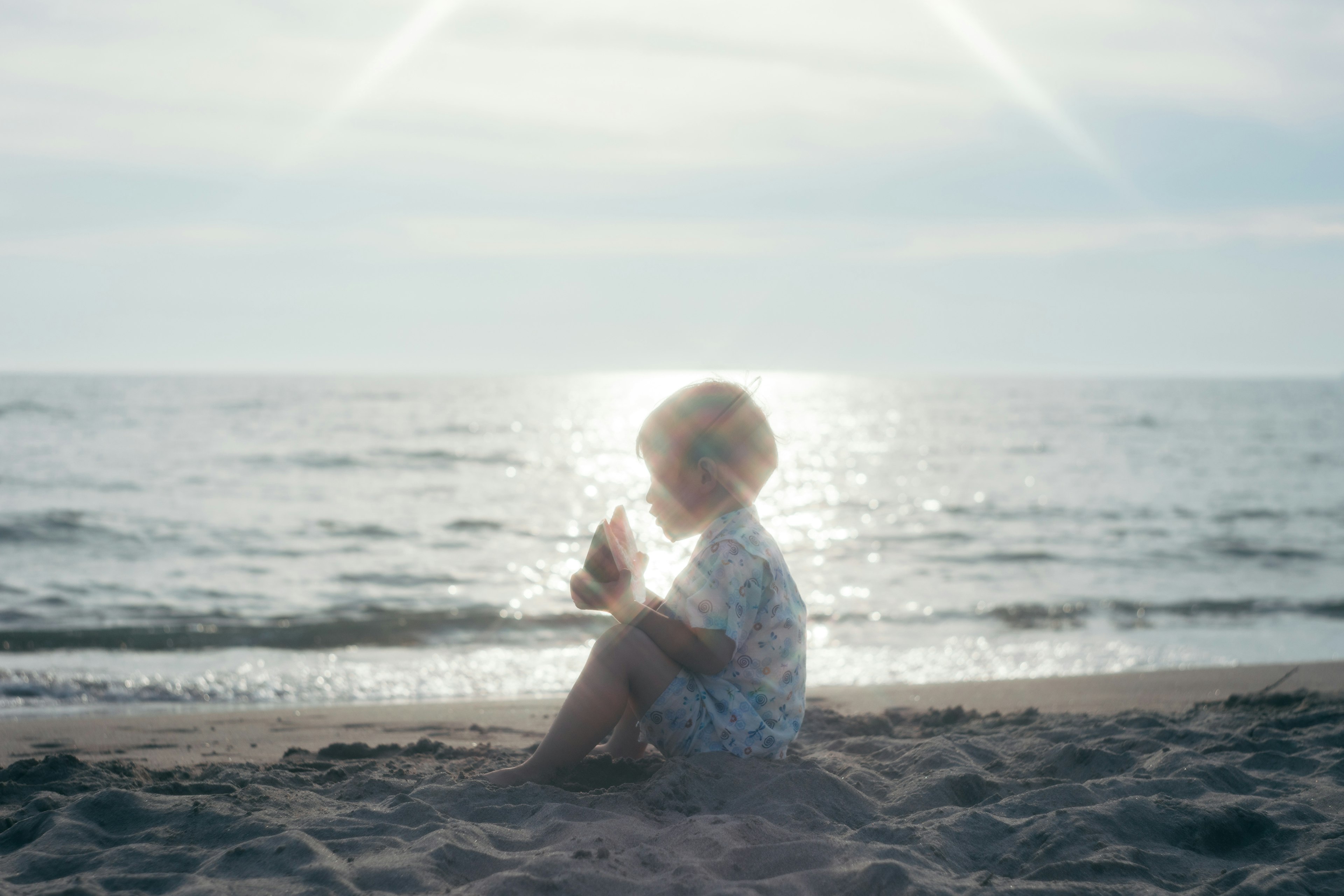 Silhouette of a child sitting quietly by the beach with light reflections