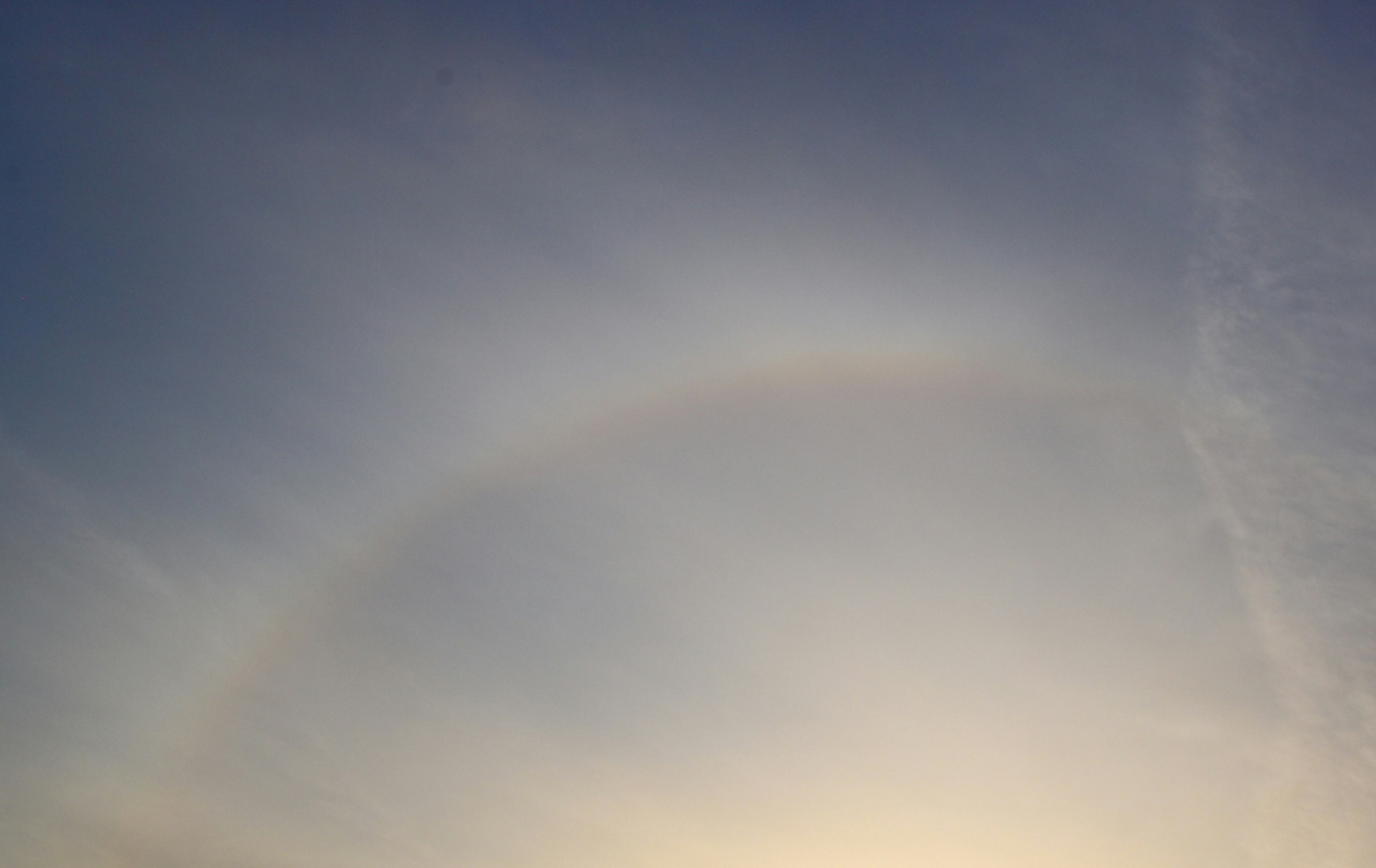 Faint rainbow arching across a blue sky