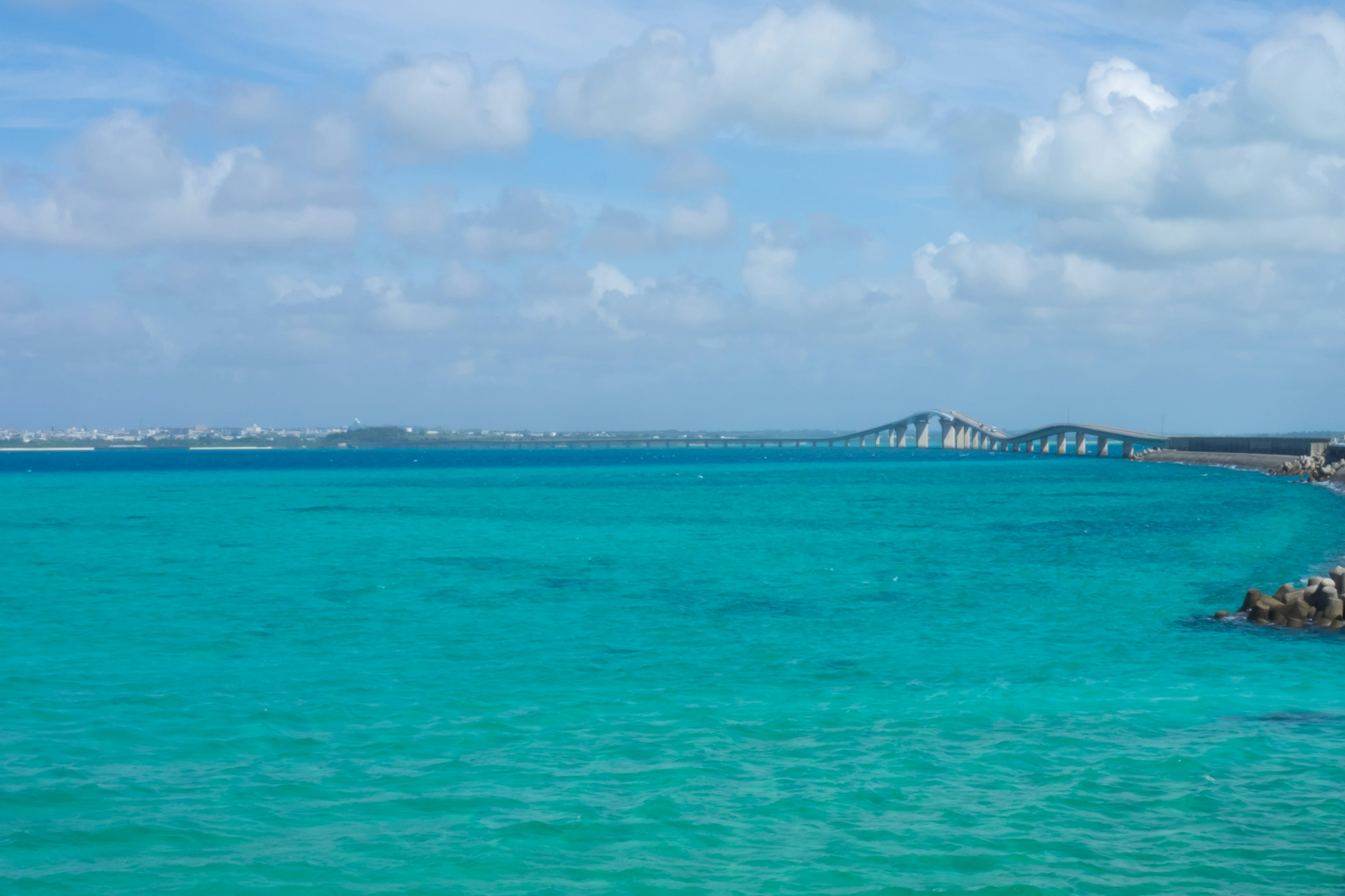 Océan turquoise vibrant sous un ciel bleu avec des nuages duveteux