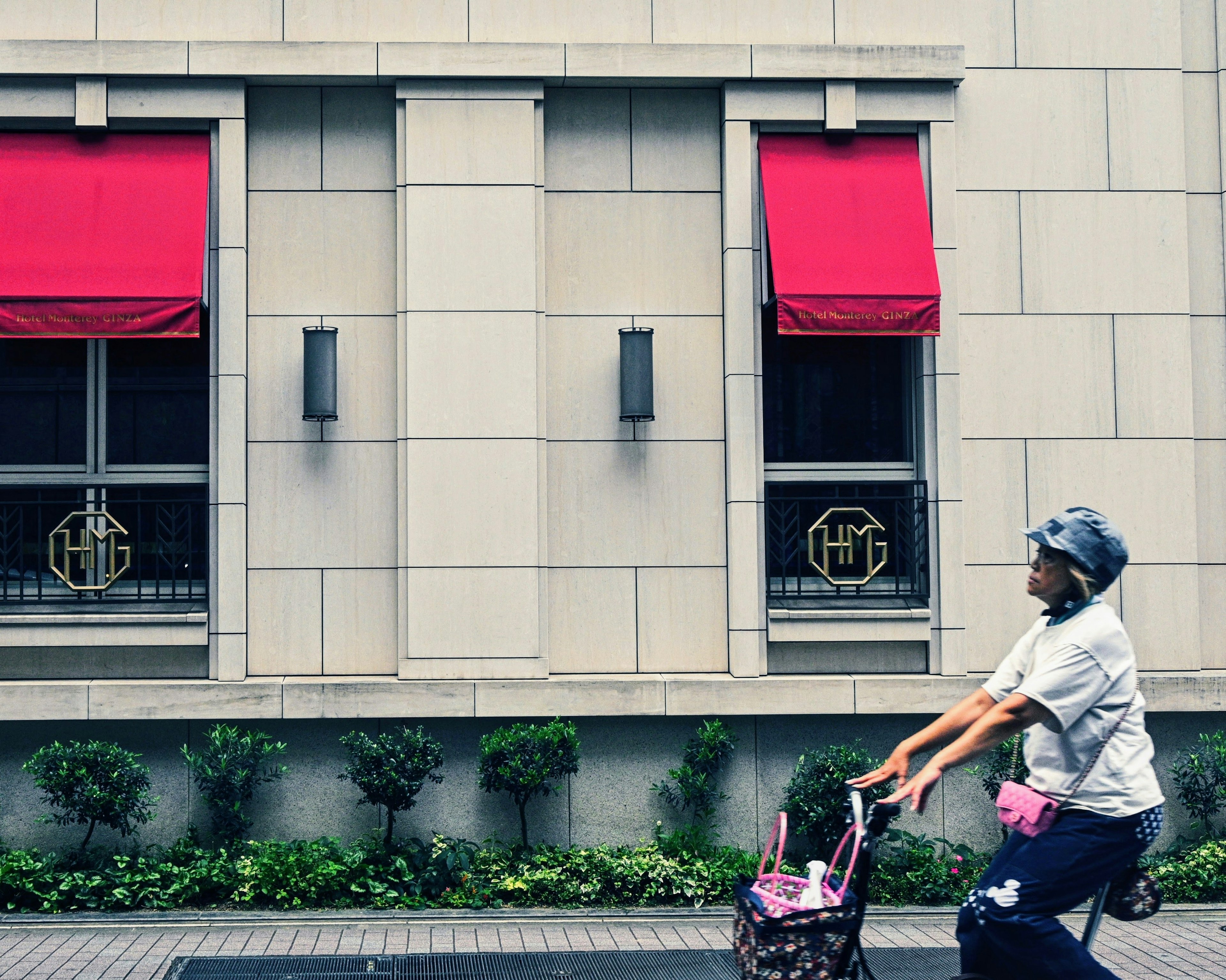 赤いカーテンがかかった建物の前をベビーカーを押して歩く女性