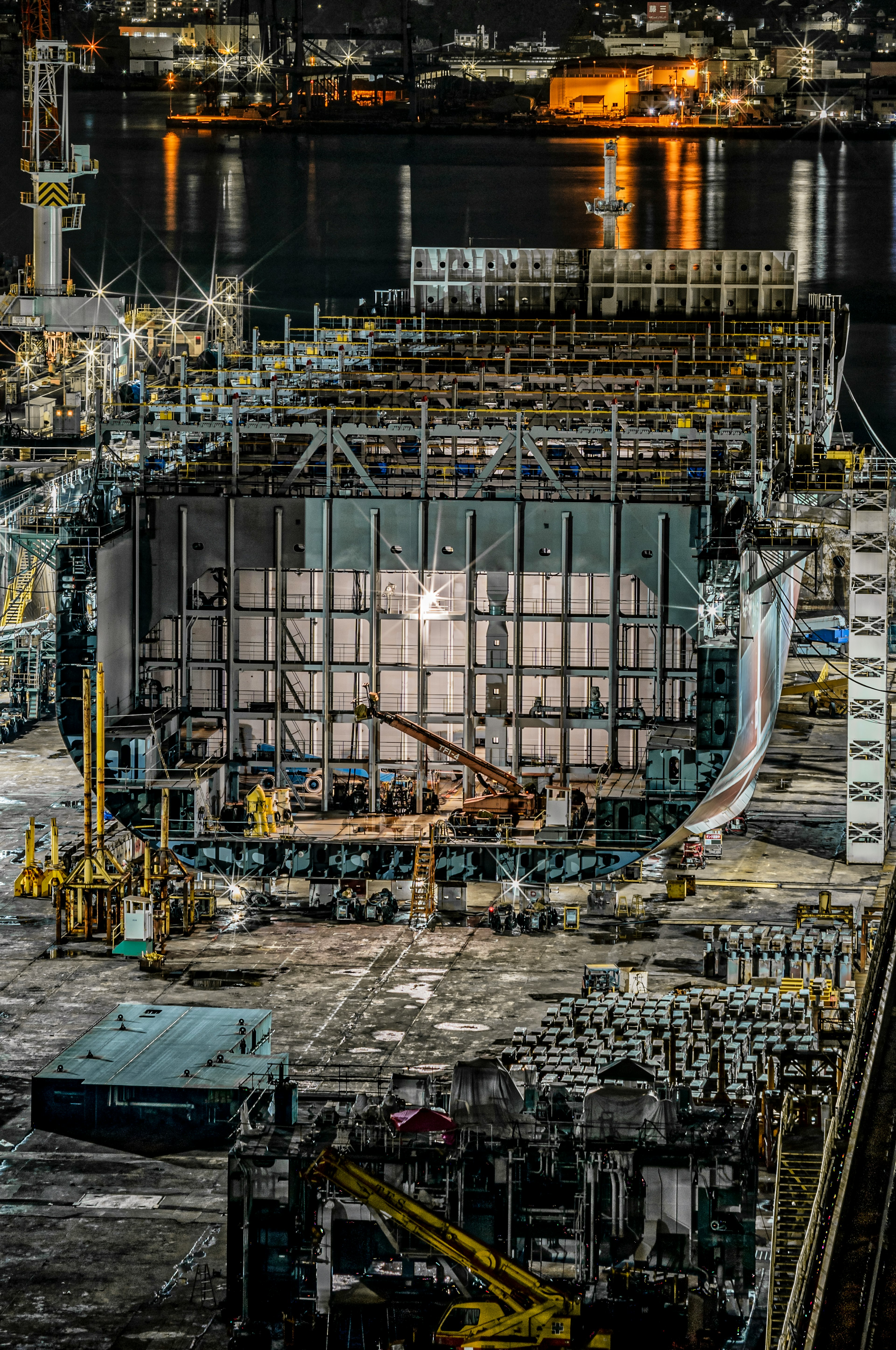 夜の港での建設現場の全景 建物の構造物と作業用クレーンが見える