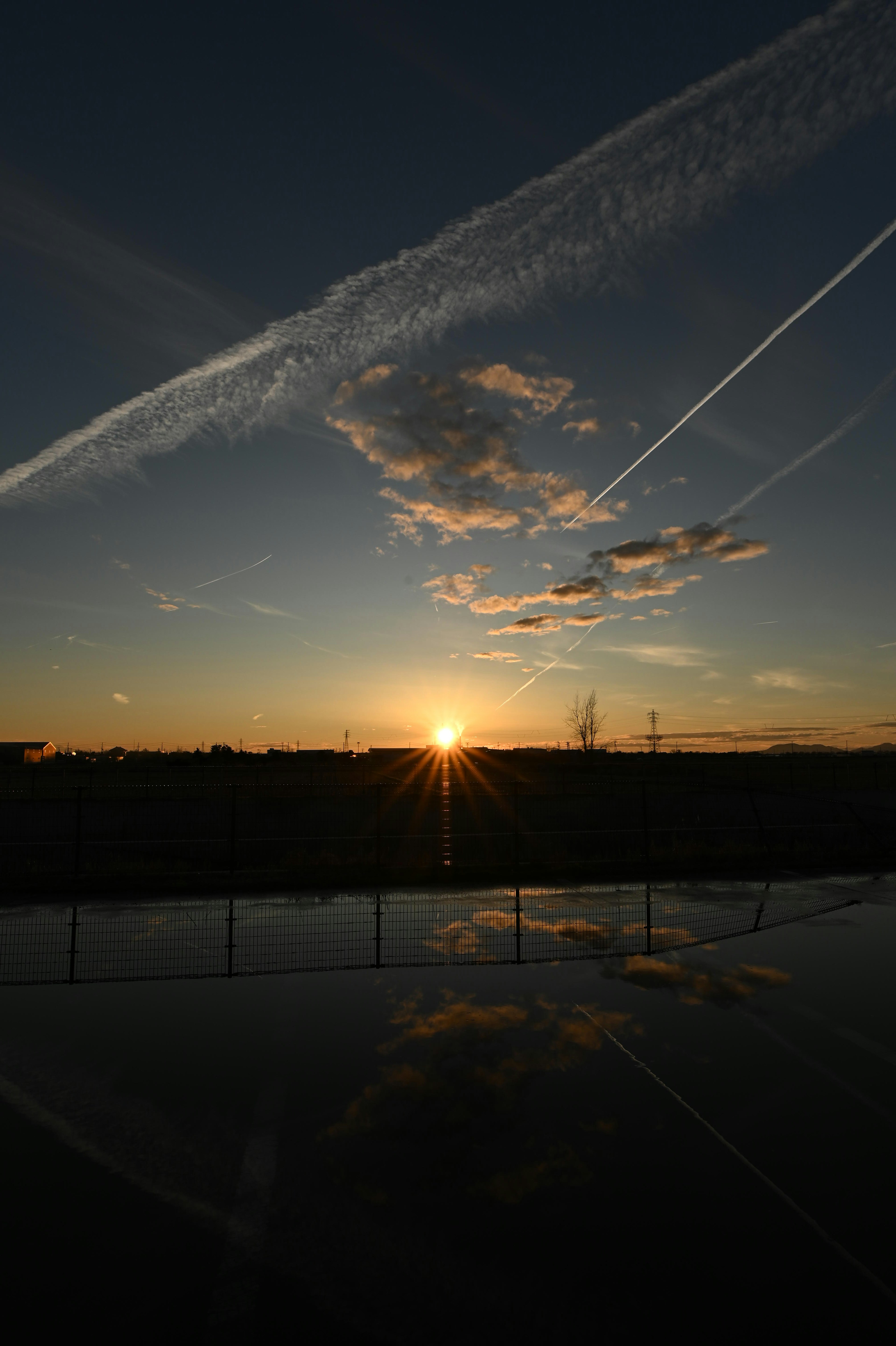 Tramonto su una superficie riflettente con nuvole nel cielo