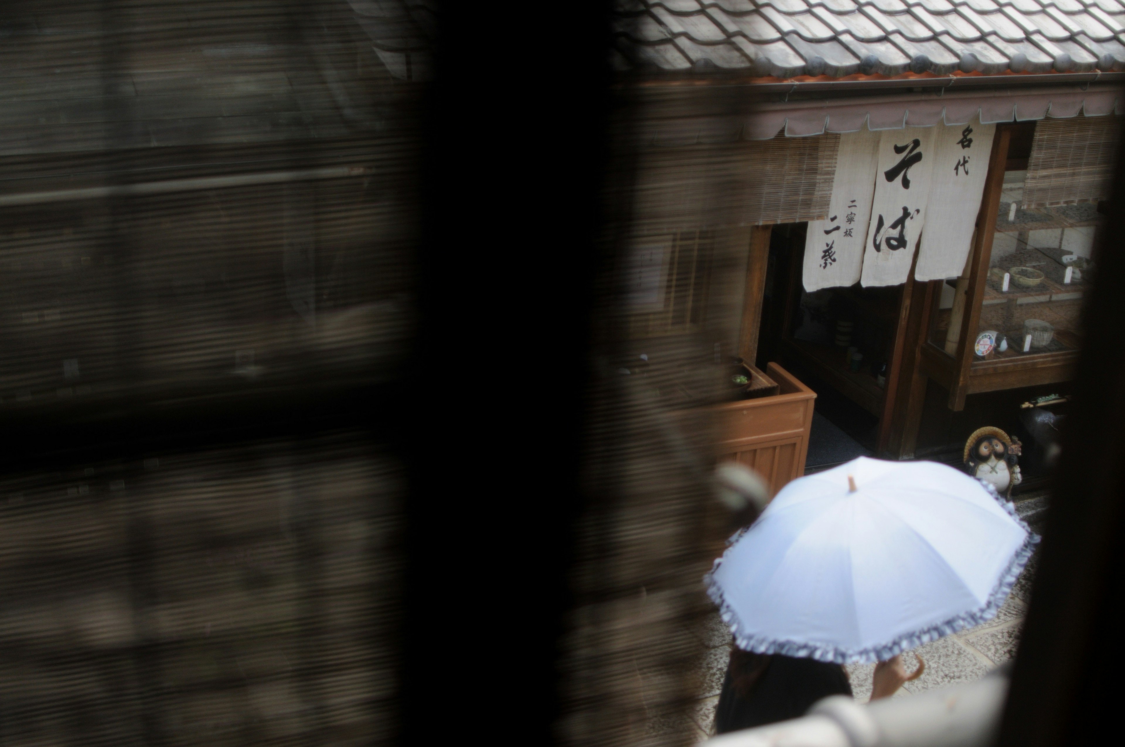 一个人走在古老建筑前，手持白色雨伞