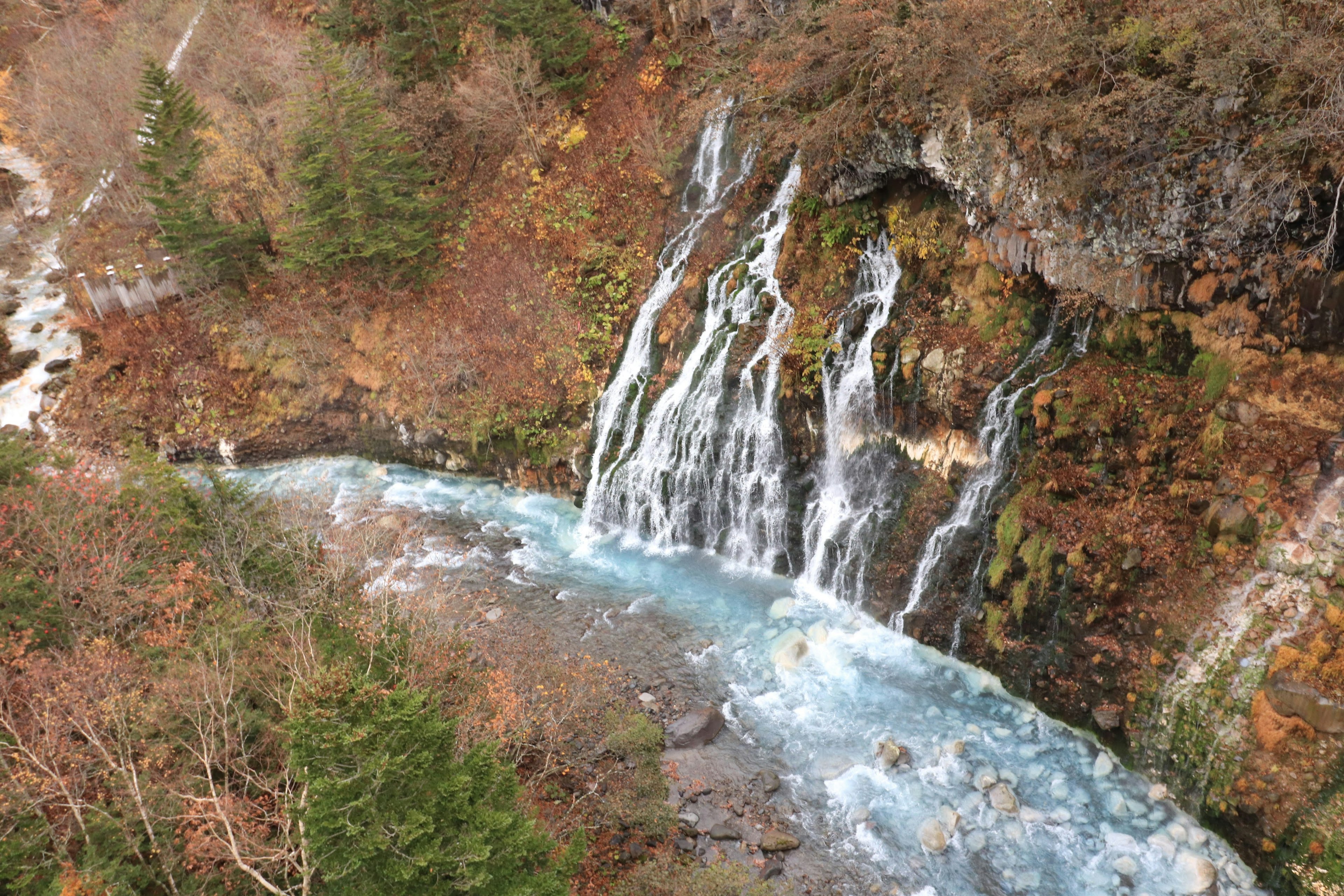 Pemandangan musim gugur dengan air terjun dan aliran biru