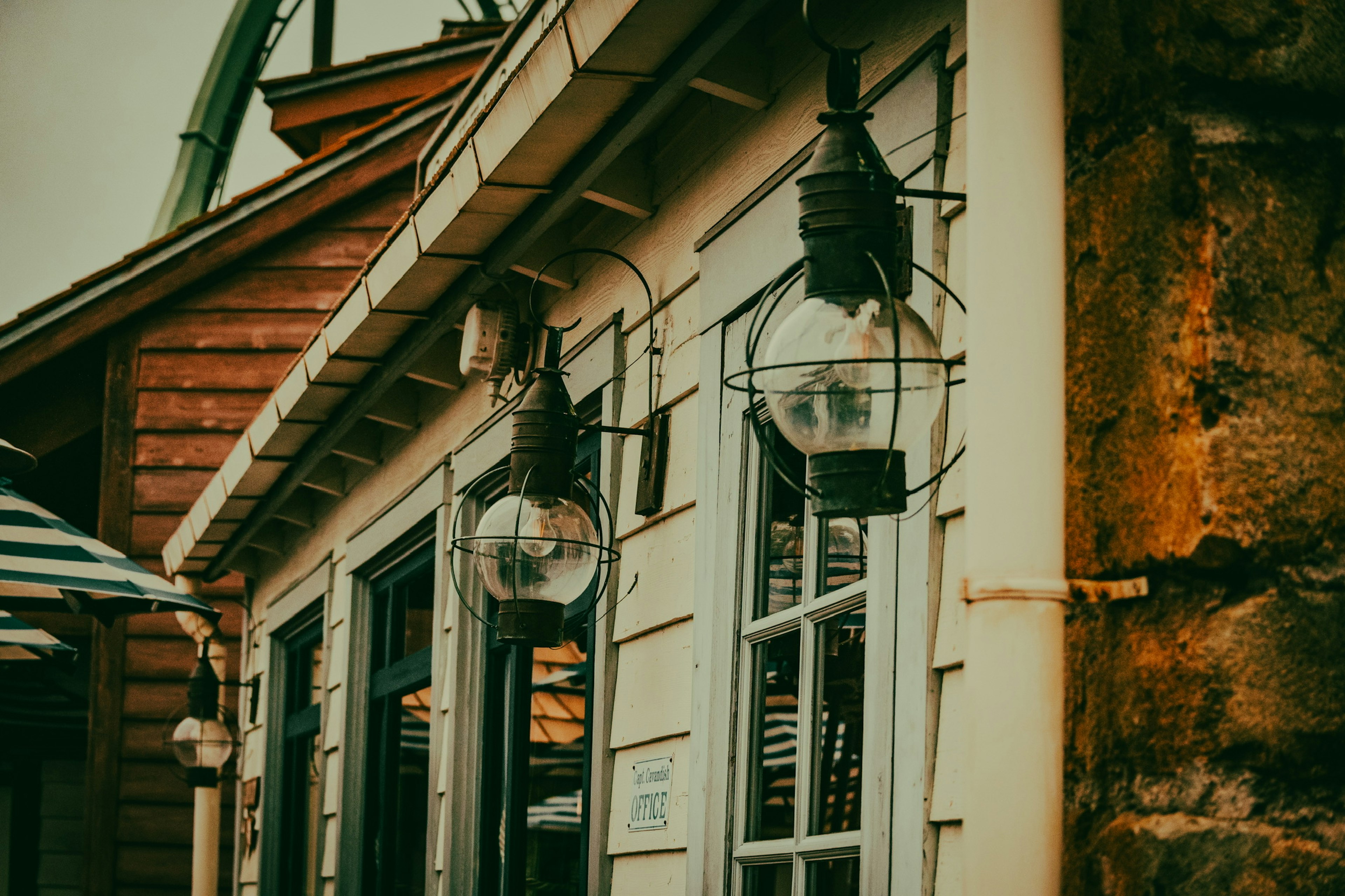 Glass lanterns hanging on the wooden exterior of a house with white windows