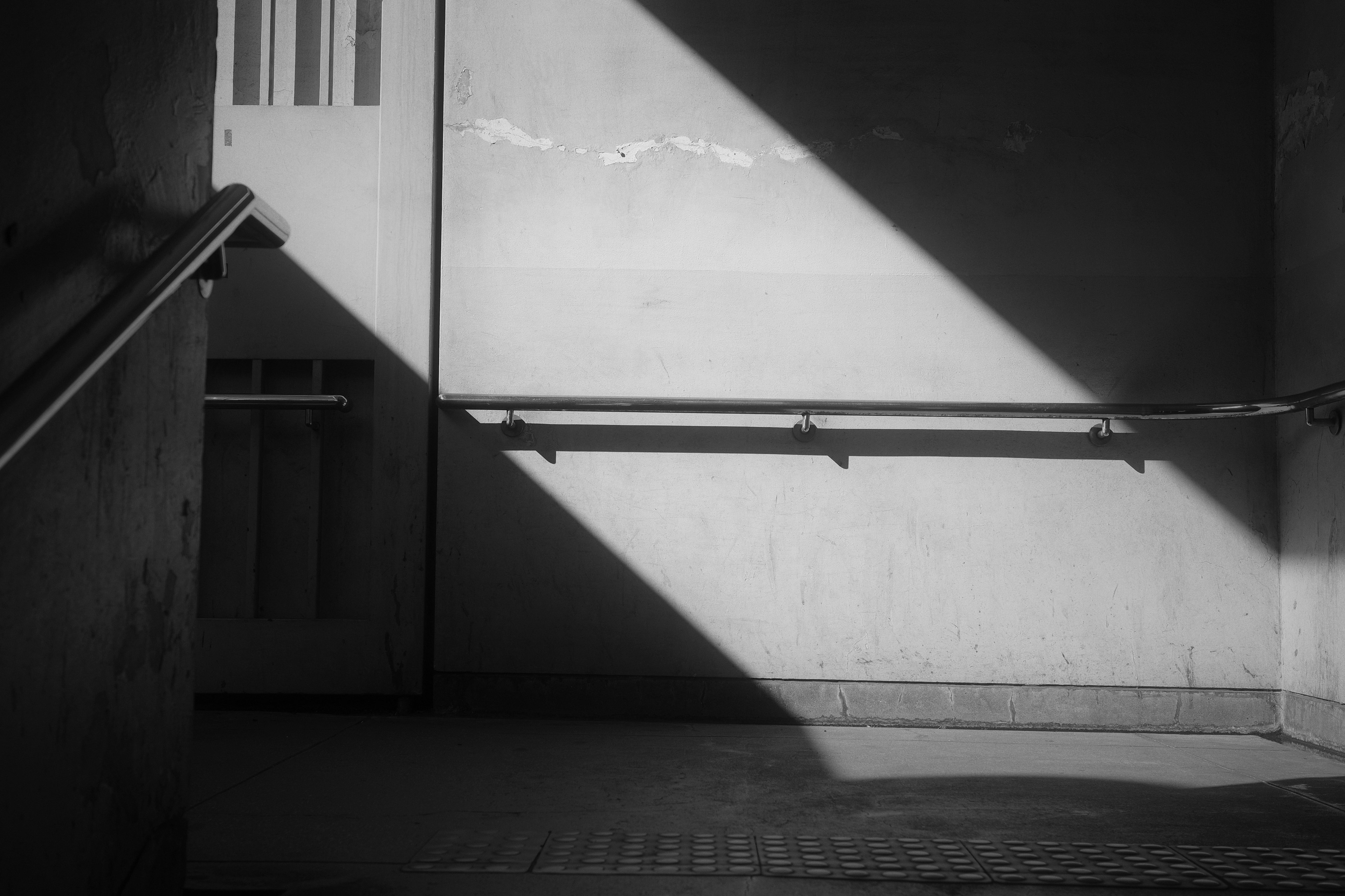 Monochrome space featuring a staircase railing and contrasting shadows