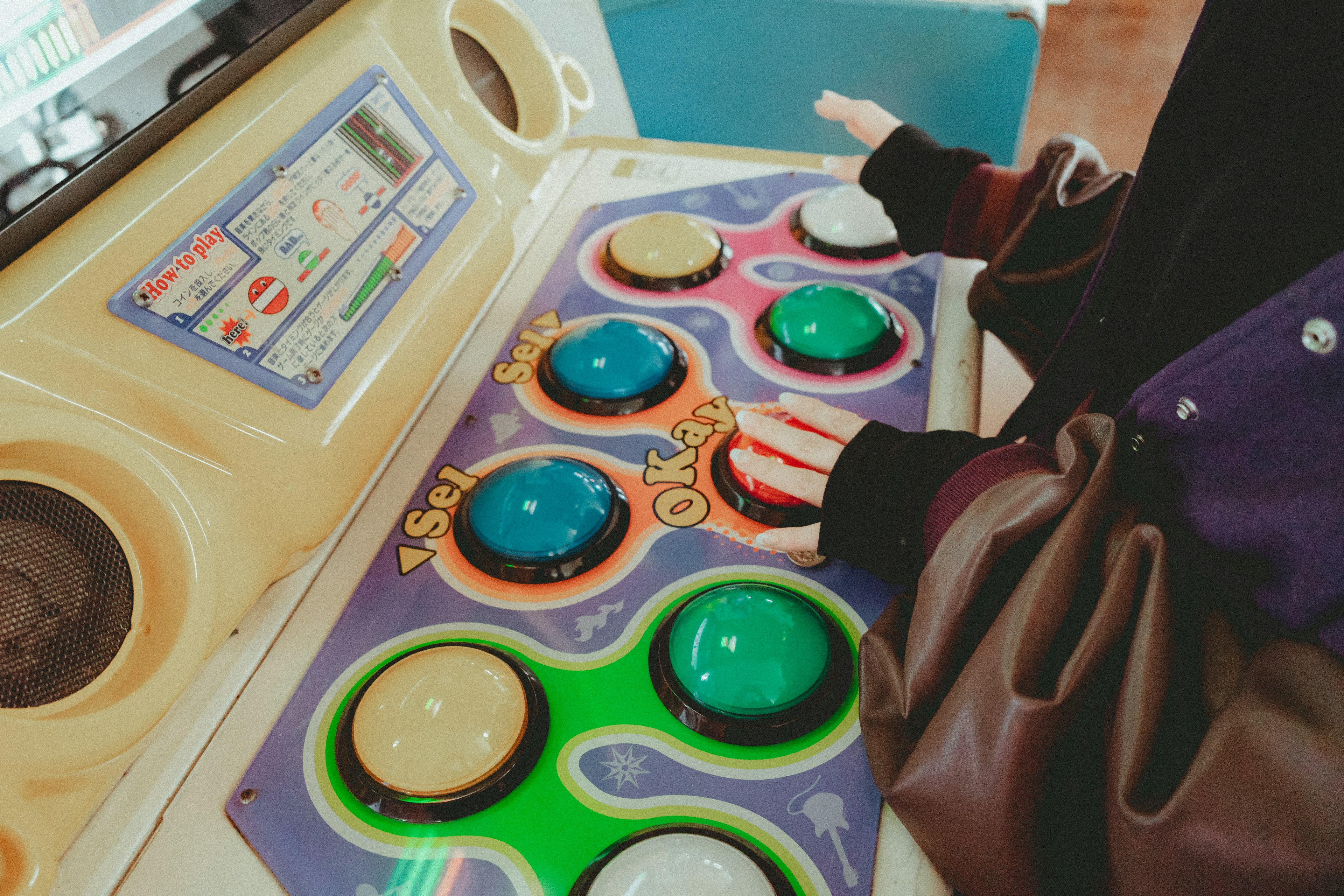 Person's hand resting on colorful buttons of an arcade game control panel