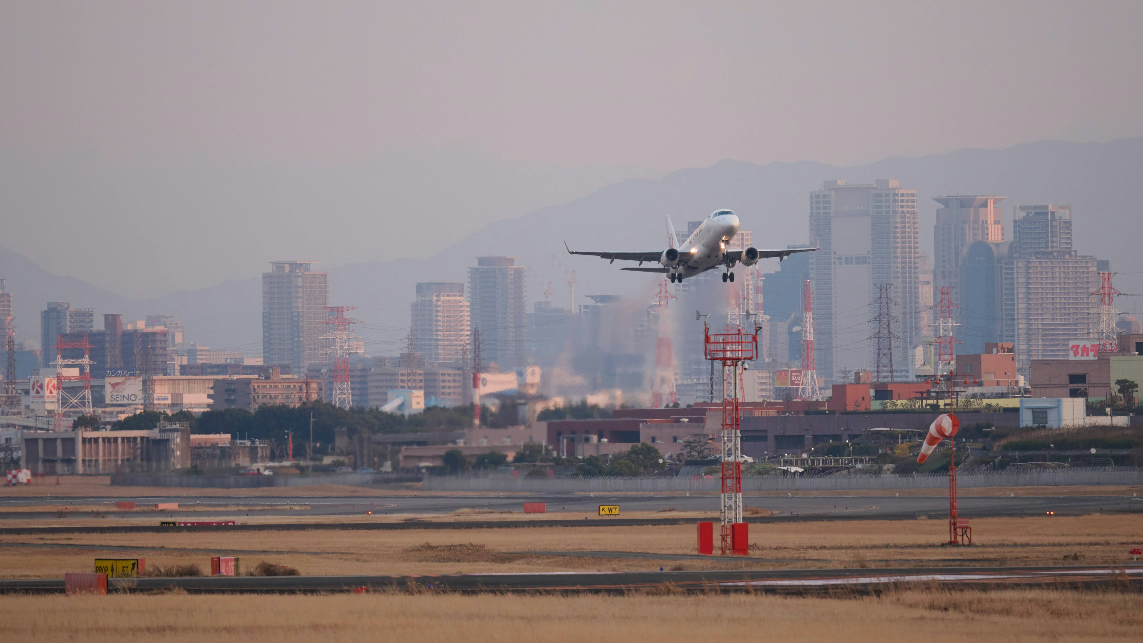 Avión aterrizando en la pista con el horizonte de la ciudad a lo lejos