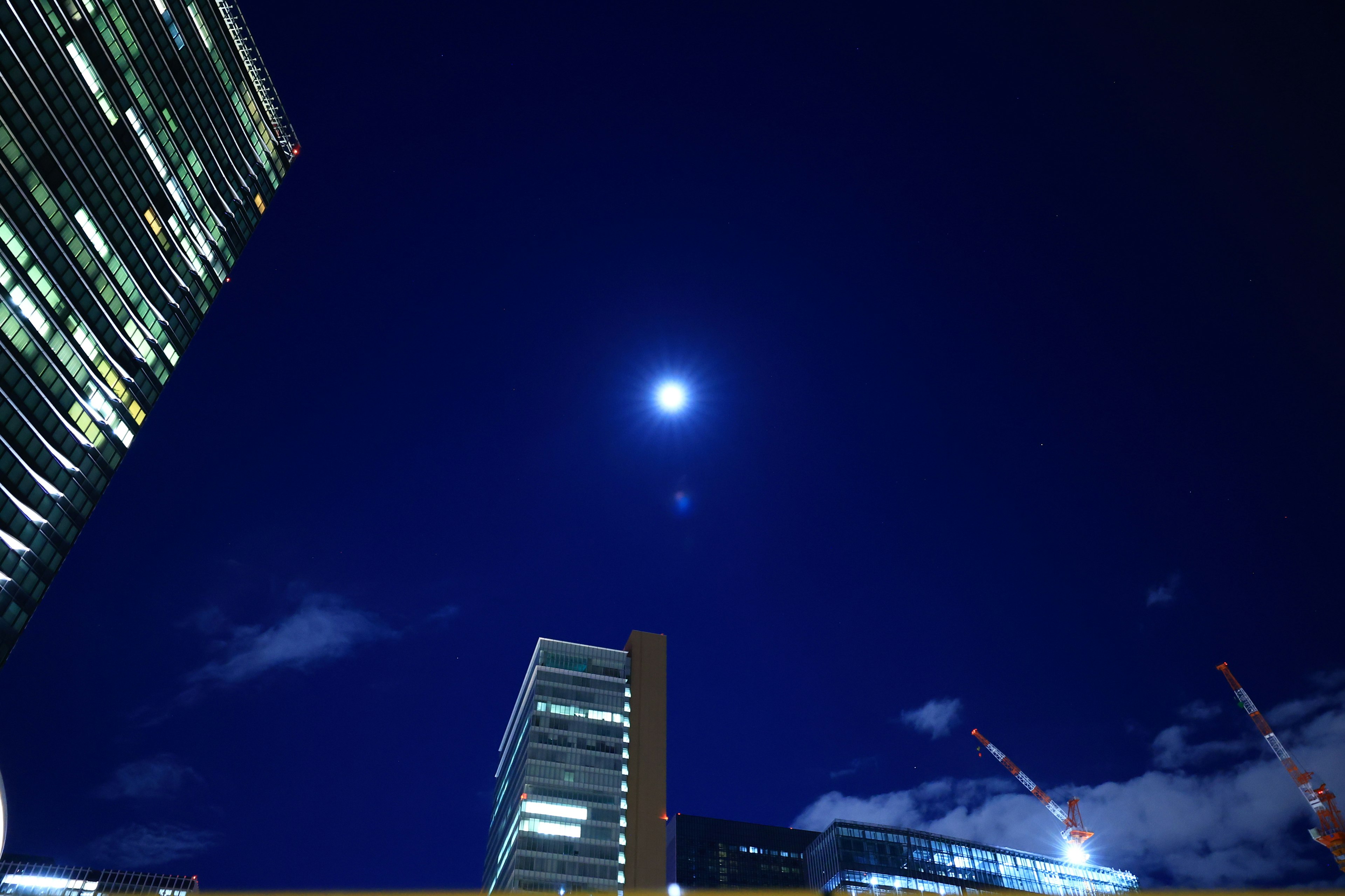 Luna brillante nel cielo notturno con silhouette di grattacieli