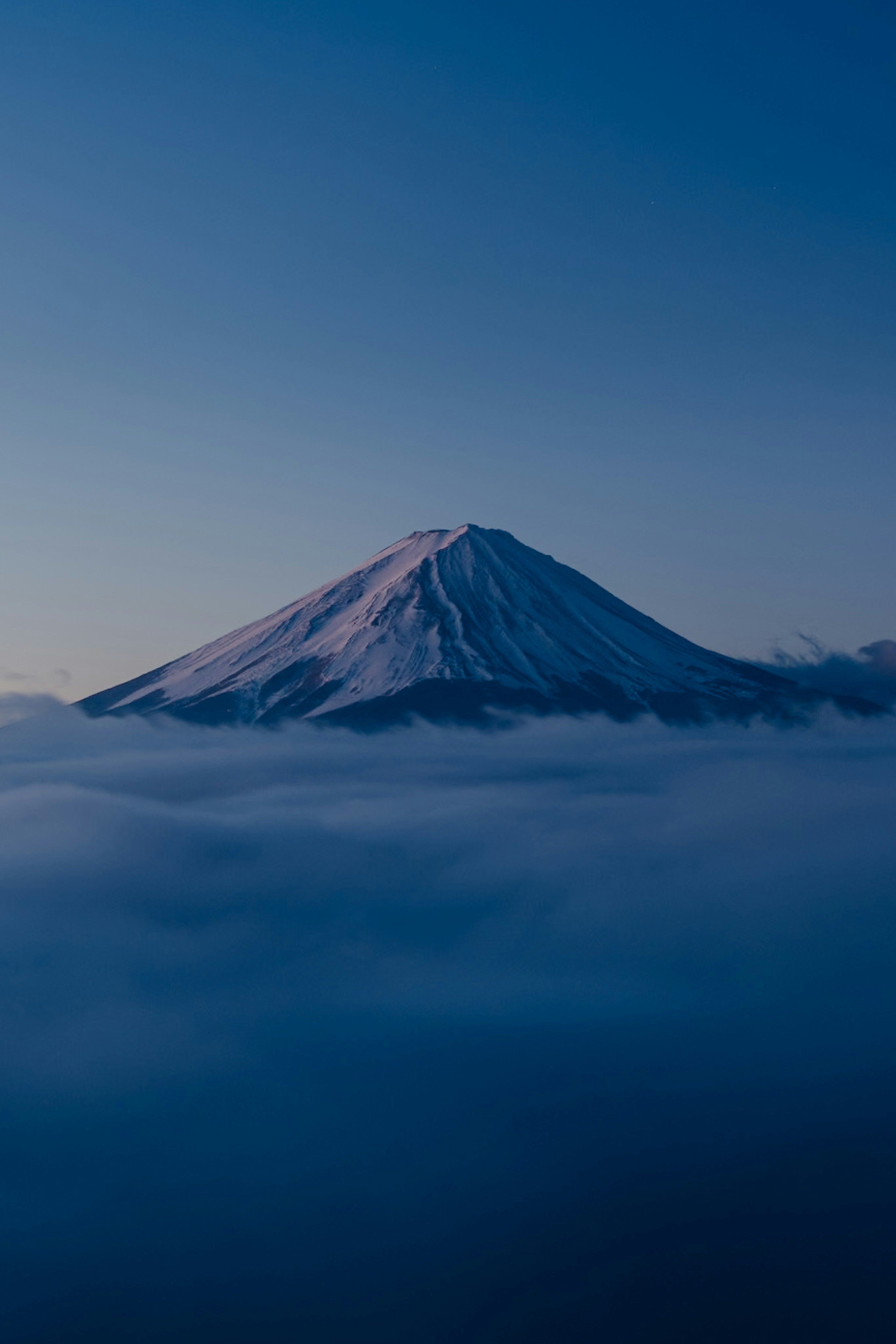 Hermosa vista del monte Fuji cubierto de nieve flotando sobre las nubes en un cielo azul