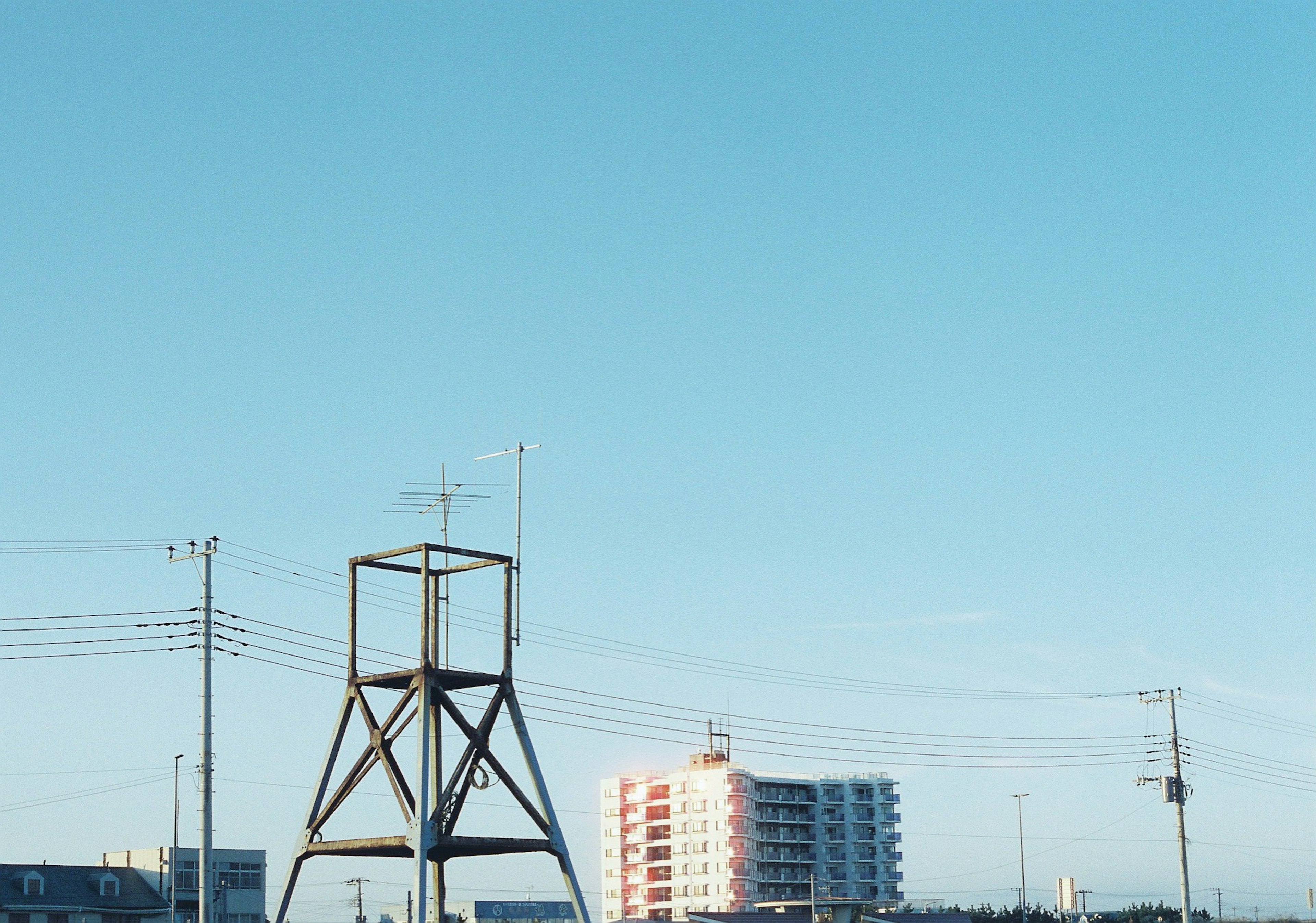 青空の下に立つ木製の塔と近くの建物