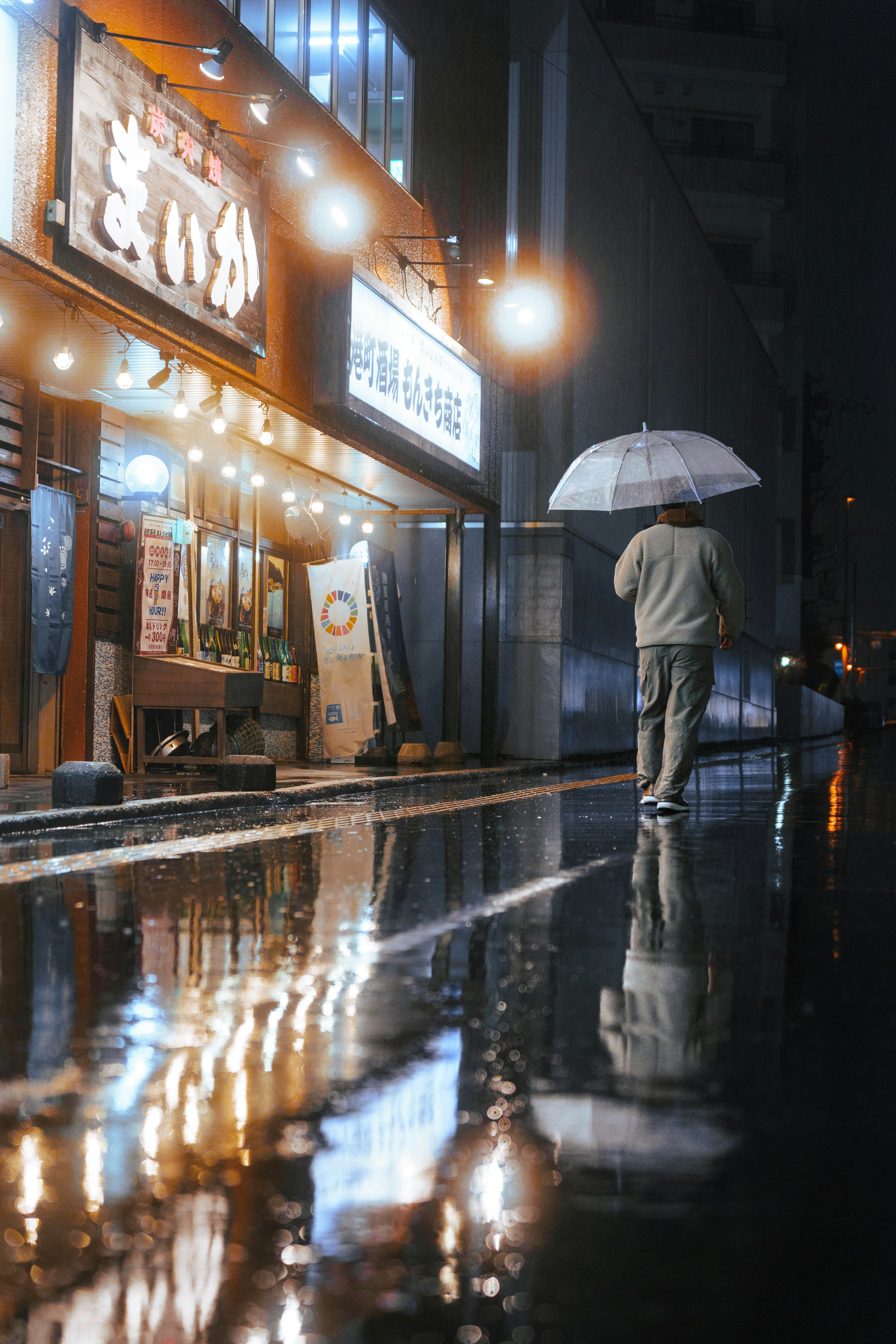 Orang yang memegang payung berjalan di jalan basah dengan refleksi