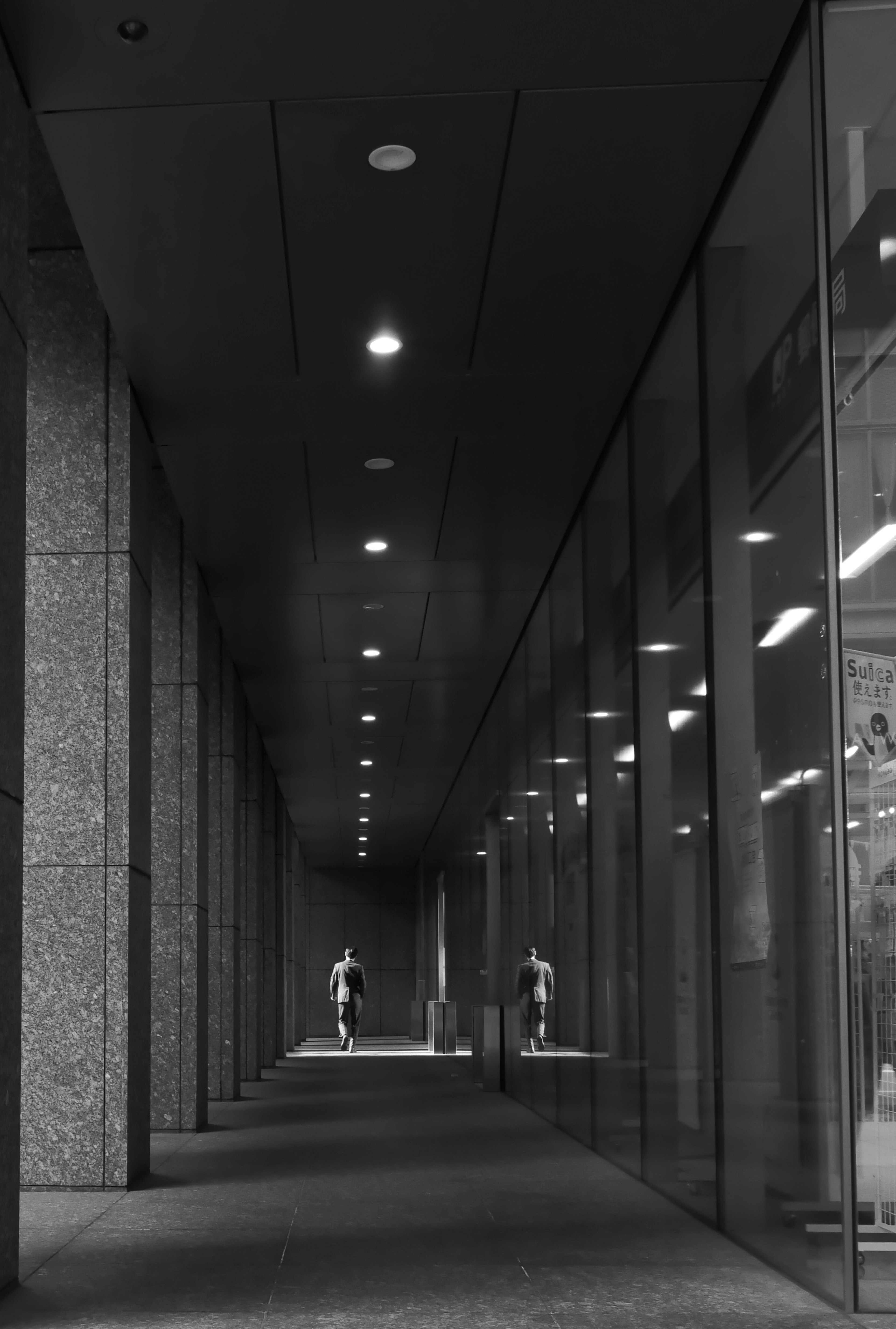 Silhouettes of two people standing in a black and white corridor of a building