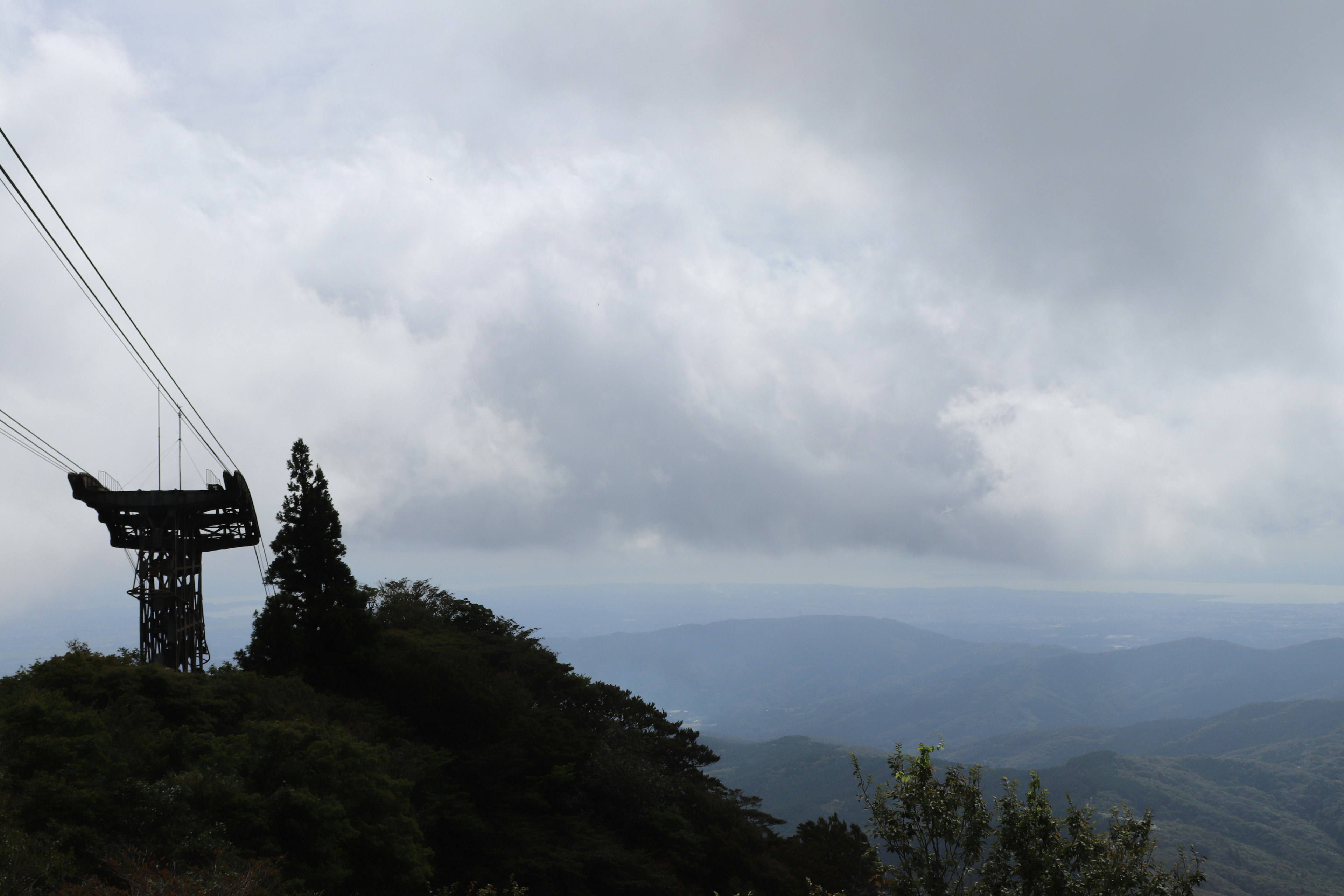 Scenic view of a cable car tower on a mountain peak with cloudy skies