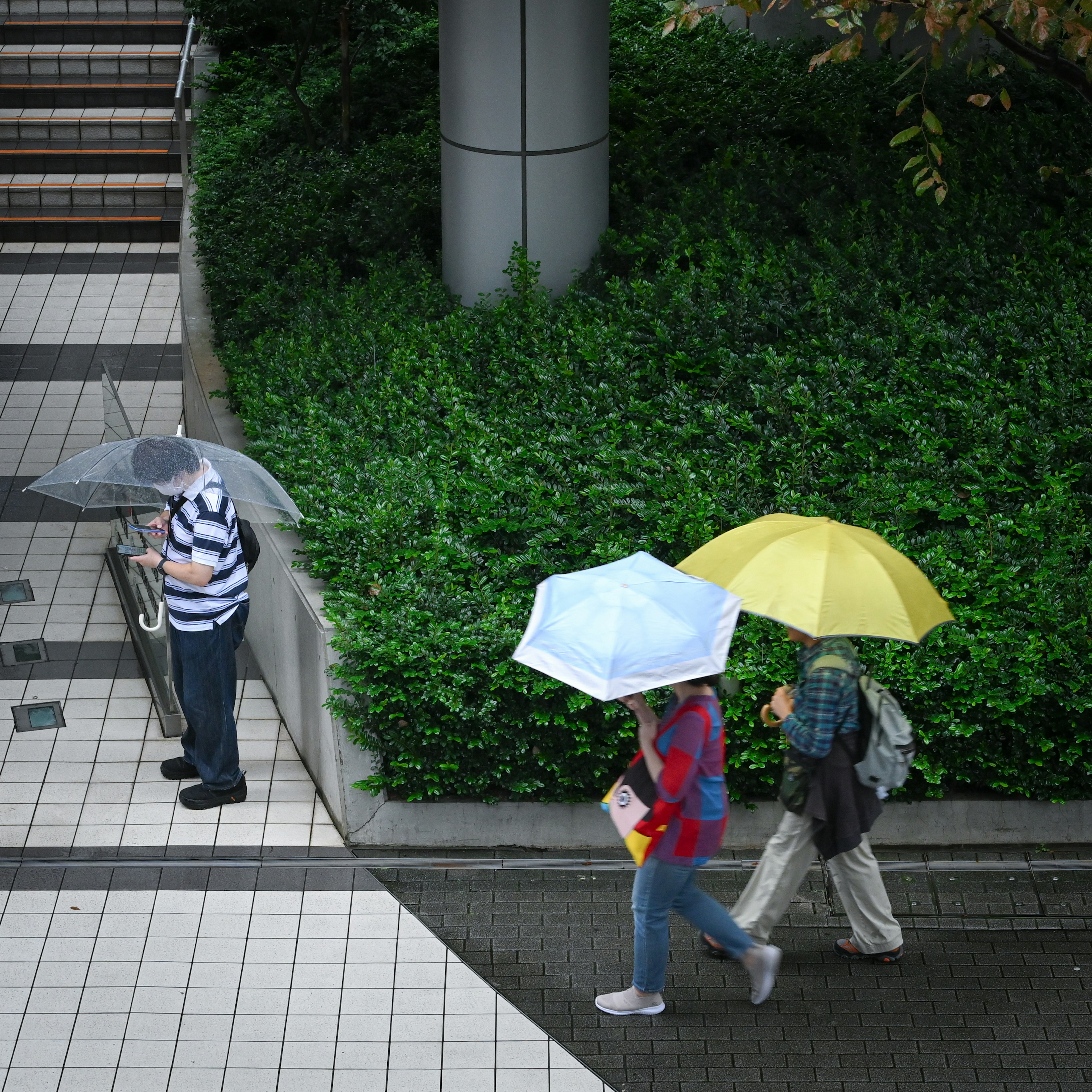 Stadtansicht mit Menschen, die unter Regenschirmen gehen