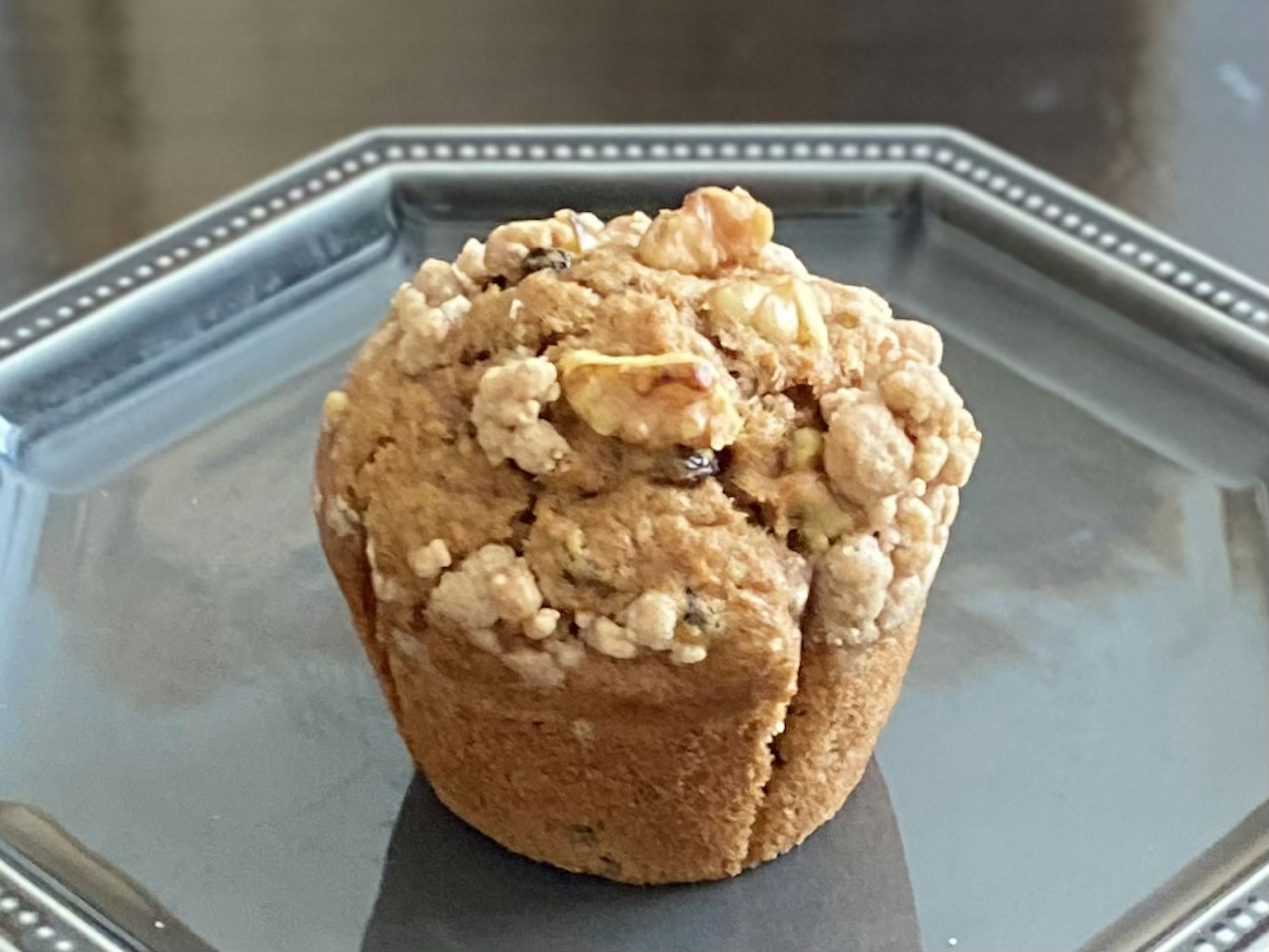 A delicious muffin topped with nuts placed on a silver plate