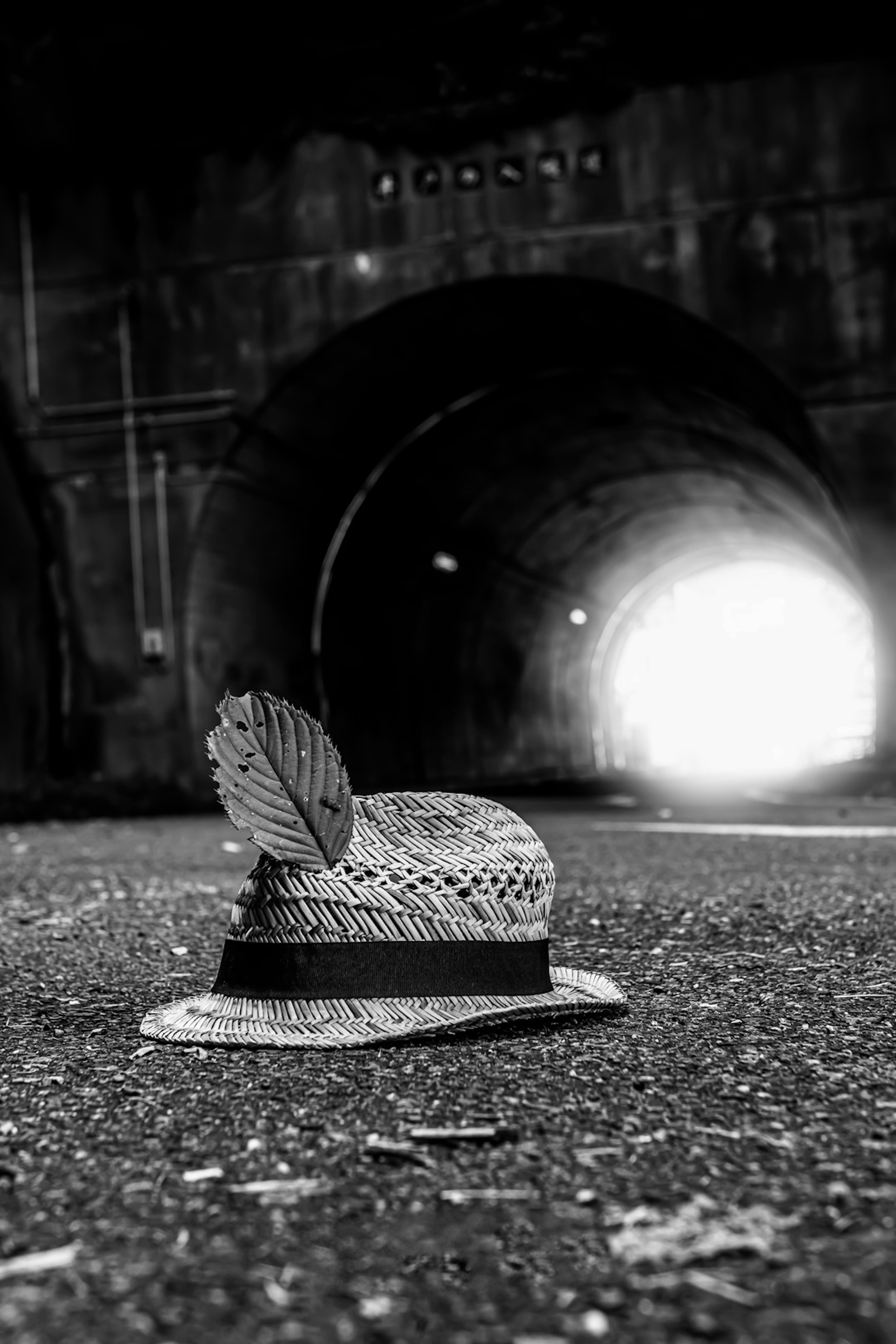 Un cappello di paglia con una piuma posato davanti a un tunnel con luce intensa