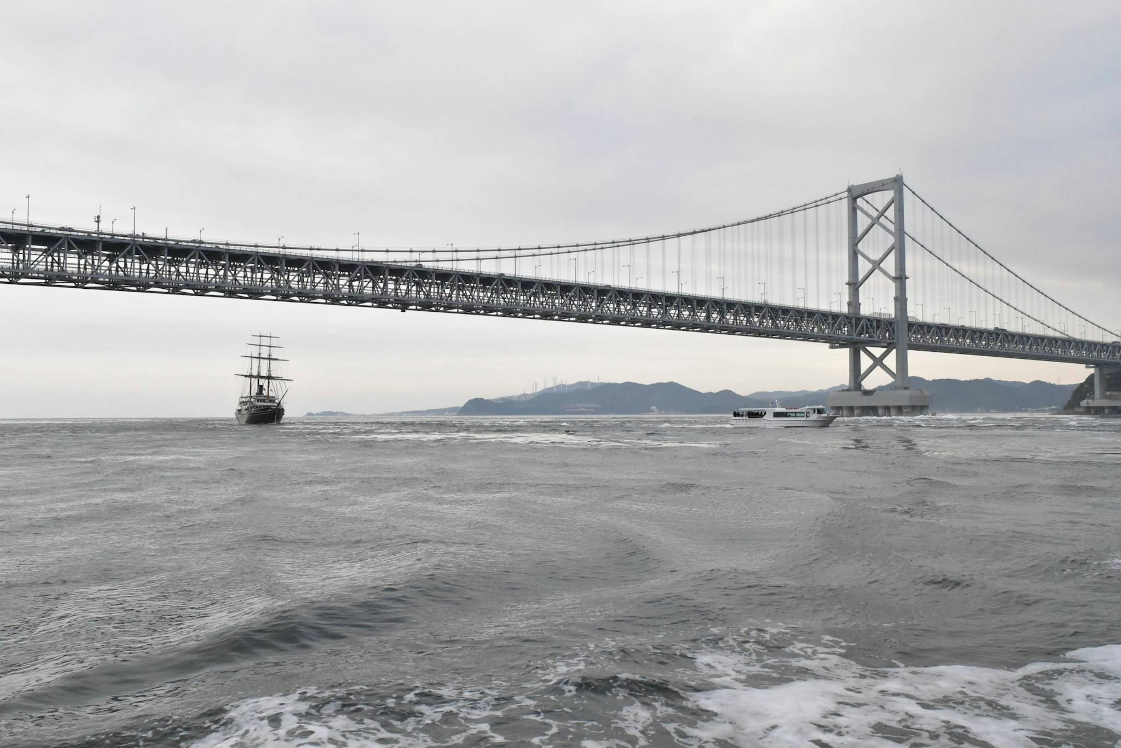 Vista de un barco en el mar con un puente al fondo