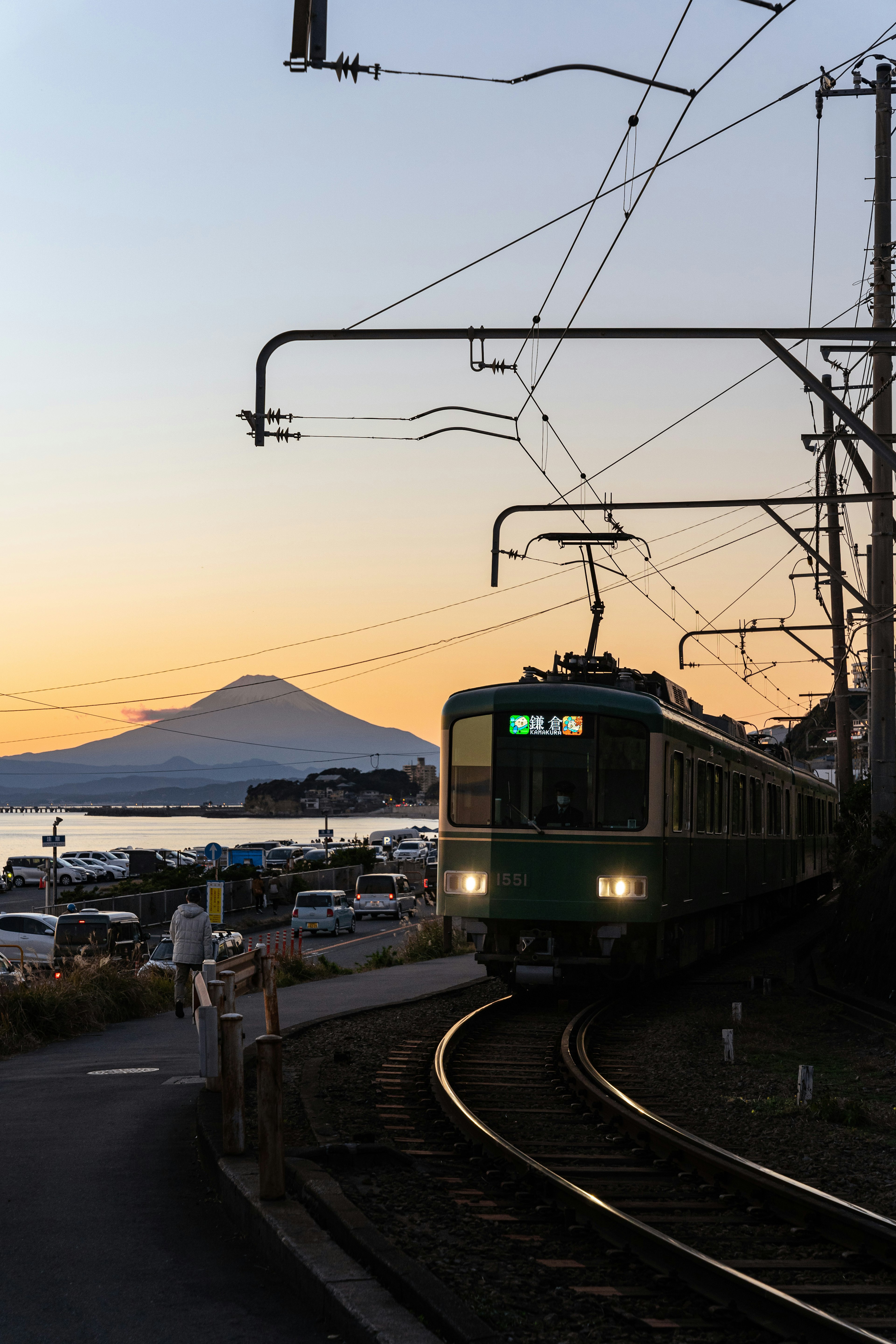 Zug, der entlang der Küste mit dem Fuji im Hintergrund während des Sonnenuntergangs fährt