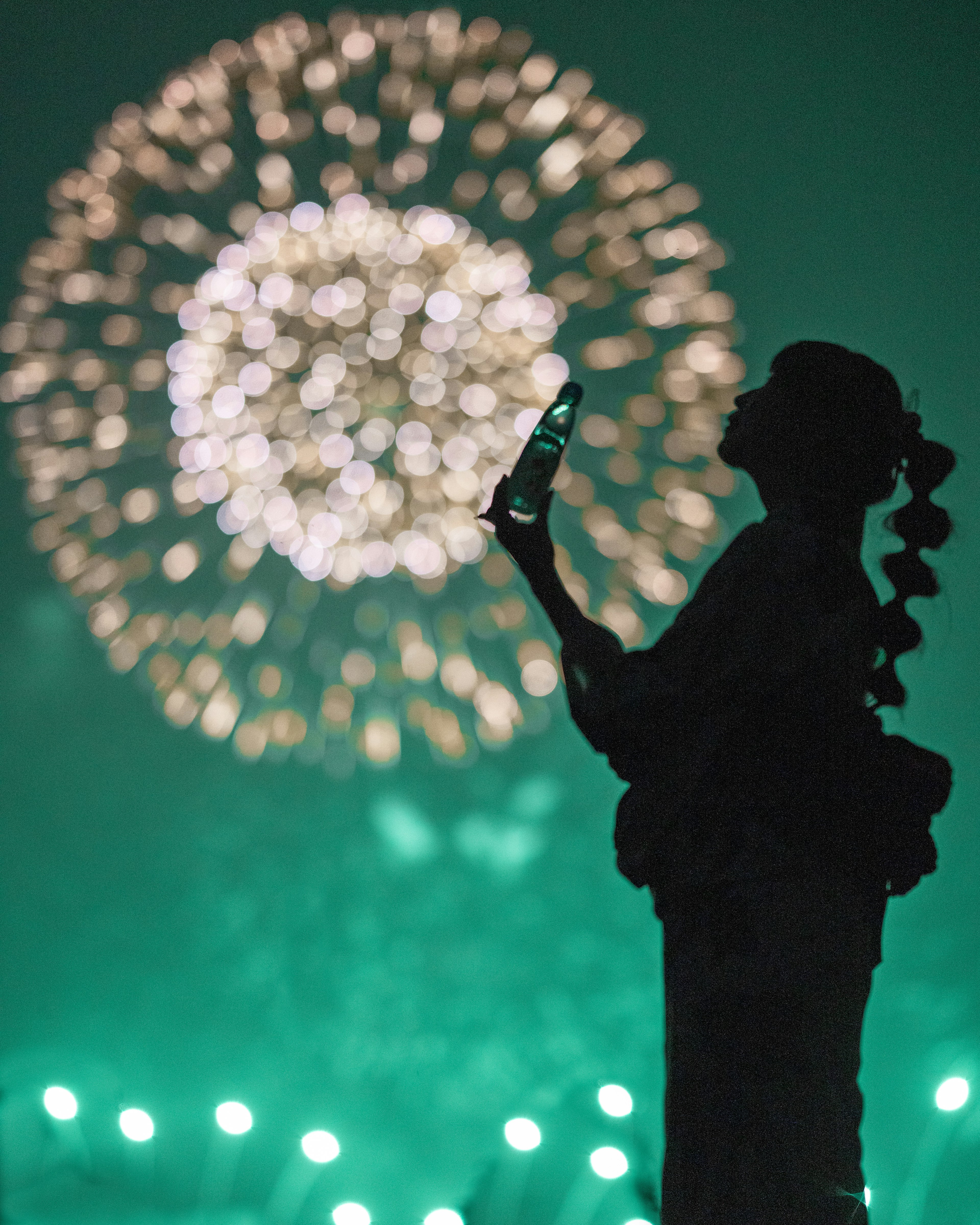 Silhouette di una donna in kimono contro uno sfondo di fuochi d'artificio nel cielo notturno