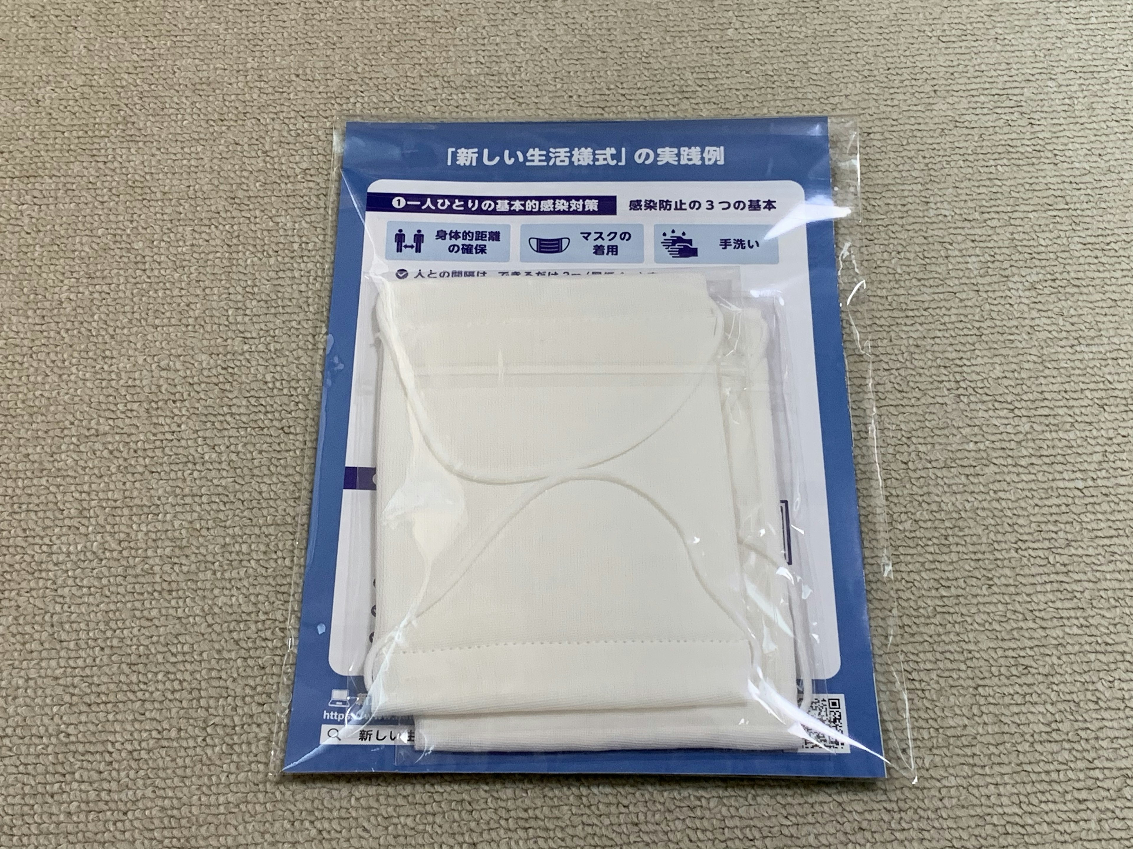 A packaged white mask product with a blue background label featuring Japanese text