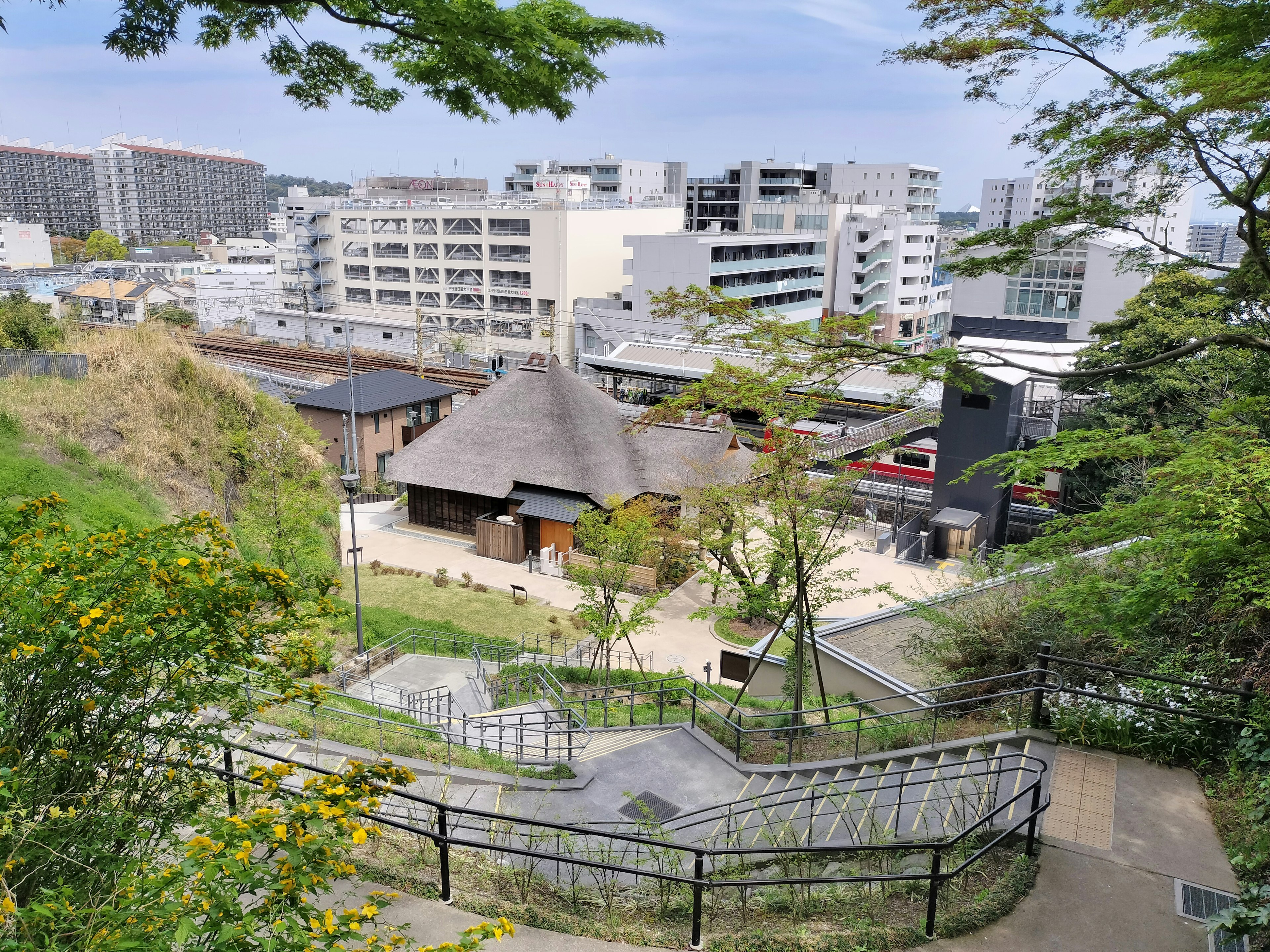 緑豊かな公園の中にある伝統的な日本家屋と現代の建物の風景