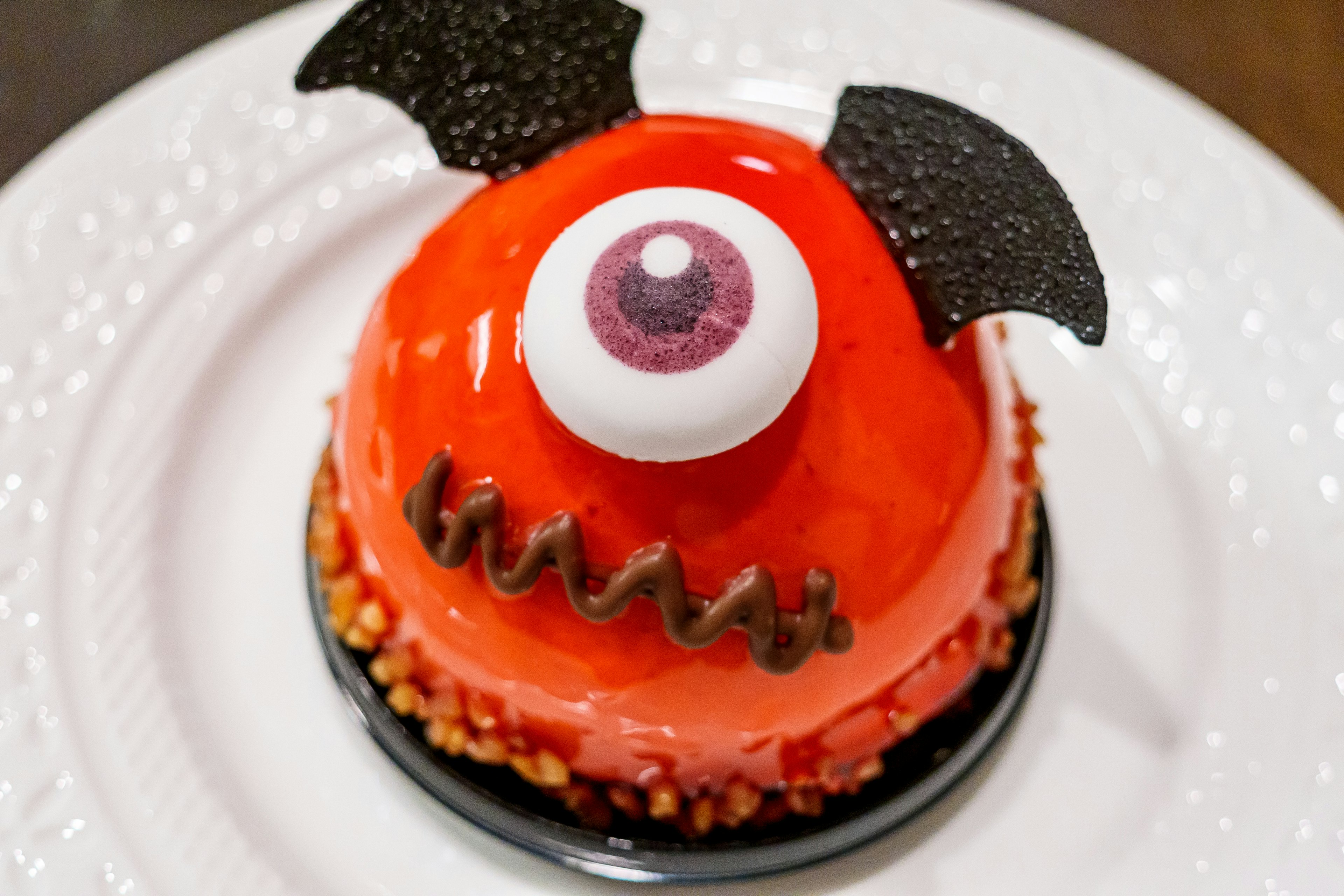 Kue monster merah dengan desain mata besar dan telinga hitam