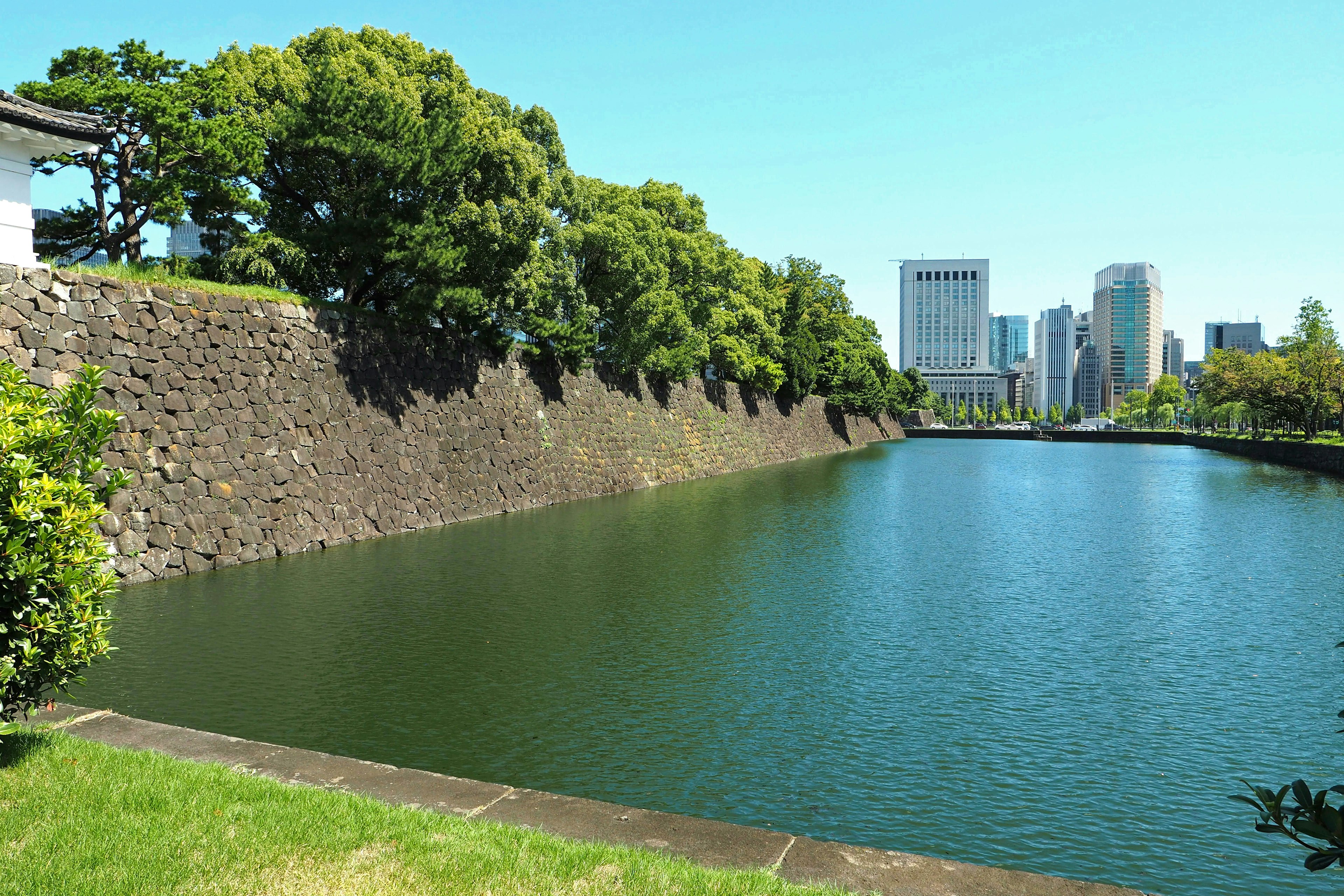 Vue des murs du château de Tokyo et du fossé avec de la verdure et des bâtiments modernes