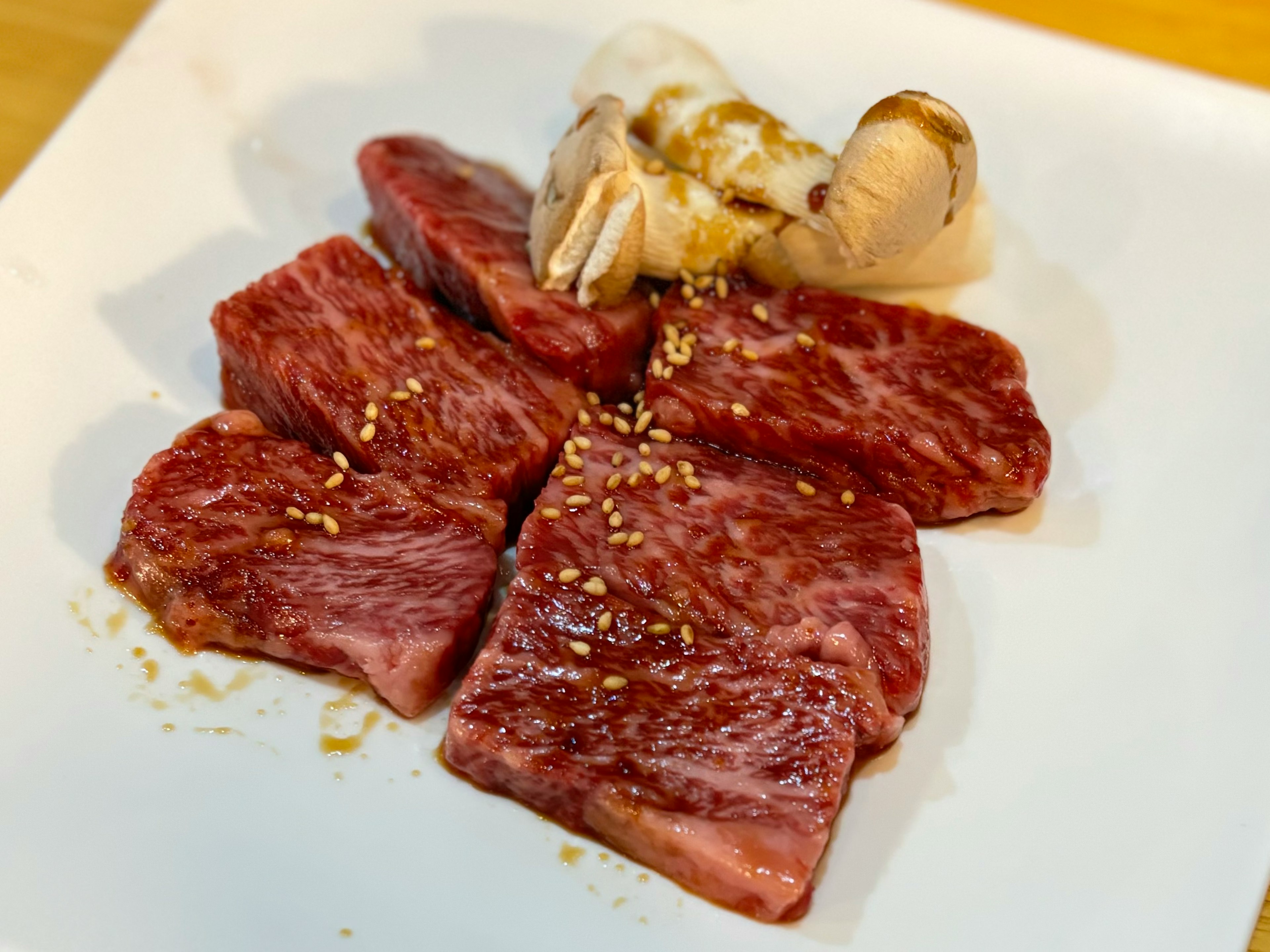 Plate of beautifully marbled wagyu beef slices with a piece of garlic