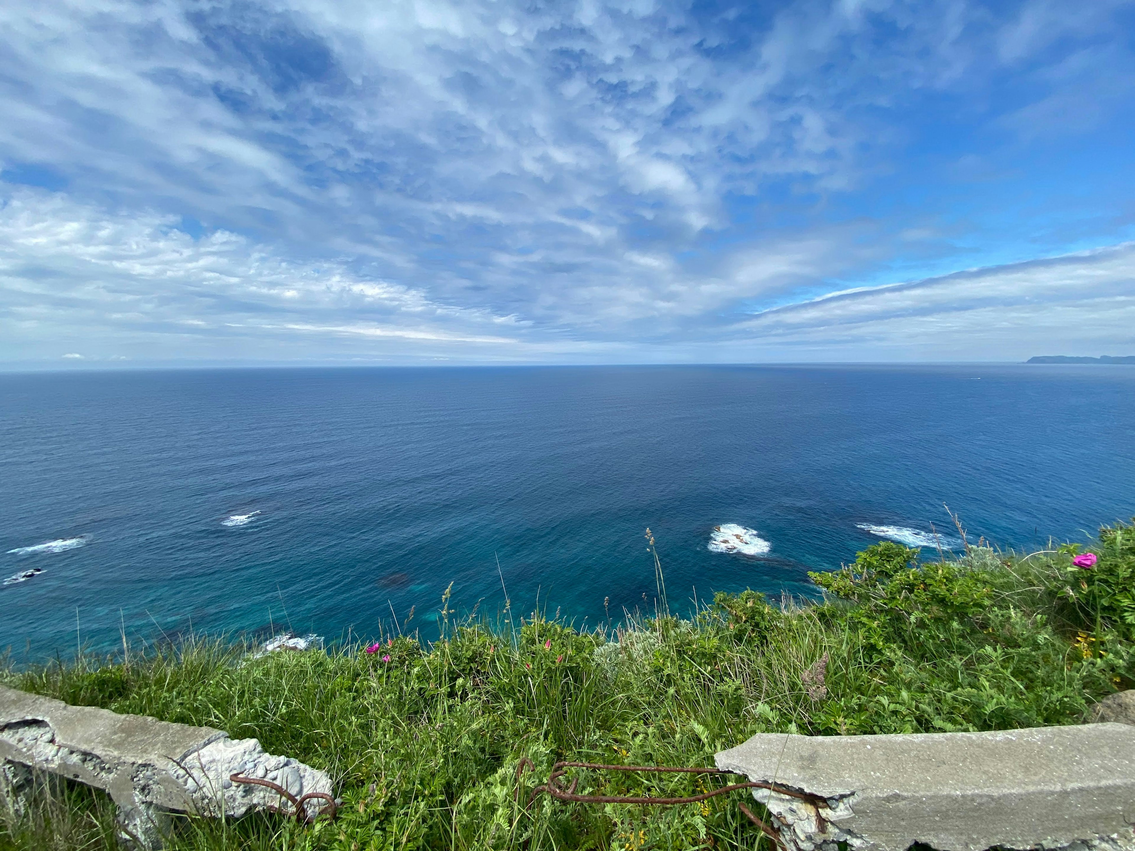 Schöne Landschaft mit weitem blauen Meer und Himmel mit Gras und Felsen